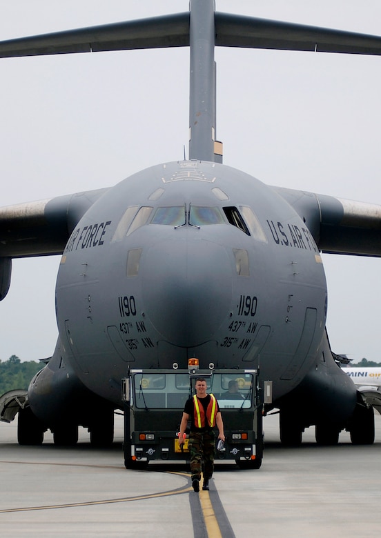 Staff Sgt. Andrew Phillips, crew chief in the 437th Aircraft Maintenance Squadron gold productions, starts the first step in a home station check by towing a C-17 to the wash rack. (U.S. Air Force Photo/Airman 1st Class Nicholas Pilch)