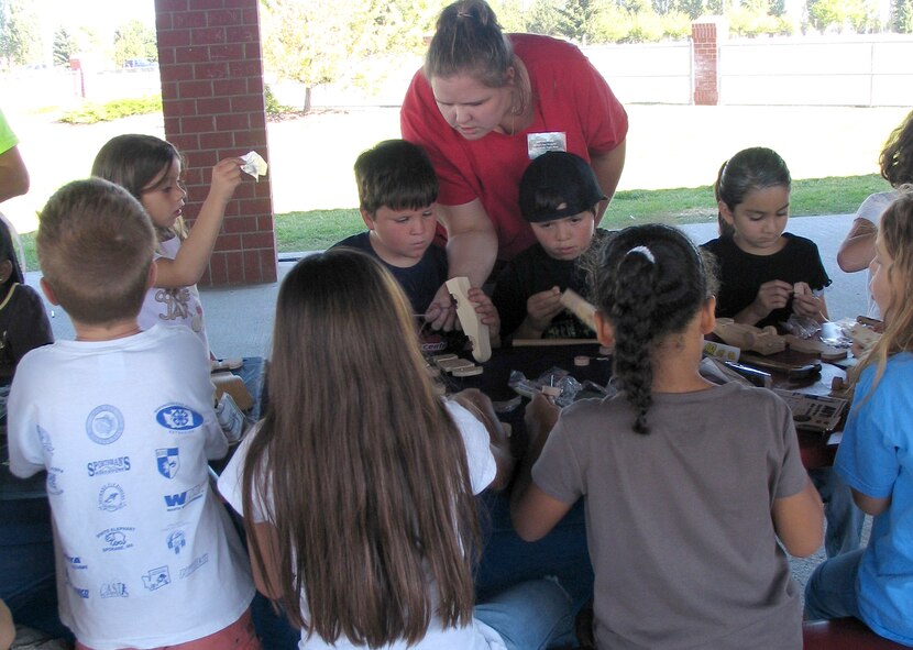 FAIRCHILD AIR FORCE BASE, Wash. – Vickie Jackson, volunteer from Lowe’s Home Improvement in Spokane Valley, Wash., helps children at the youth Center build wooden race cars at the Youth Center here Aug. 14. More than 80 children signed up for the kit-building activity at the center’s Summer Youth Program. (U.S. Air Force photo / Staff Sgt. Connie L. Bias)