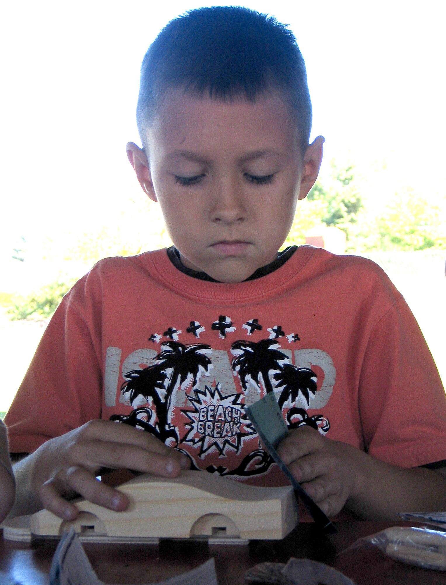 FAIRCHILD AIR FORCE BASE, Wash. -- Travis Henry, 9, smooths his wooden race car with sandpaper at the Youth Center here Aug. 14. Four volunteers from Lowe’s Home Improvement in Spokane Valley, Wash., visited the center with donated race car and bird house kits, and spent the afternoon helping more than 80 children assemble the kits. “The kids just loved it,” said Rosalyn Rupp, Youth Center lead program assistant. “To have the volunteers come in and do this was just awesome.” (U.S. Air Force photo / Staff Sgt. Connie L. Bias)