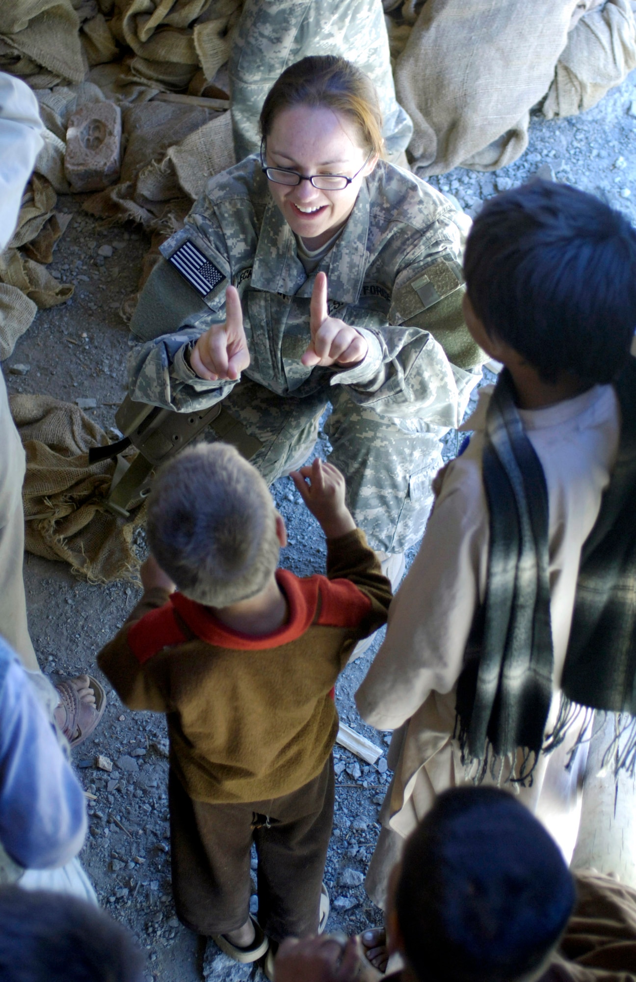 Staff Sgt. Julie Weckerlein plays a finger game with a local village boy at a school construction project Aug. 4 in the Paryan district of Panjshir Province, Afghanistan.  Sergeant Weckerlein is a print journalist deployed from the Pentagon and assigned to the U.S. Central Command Air Forces news team based in Southwest Asia. She is traveling with the Panjshir Provincial Reconstruction Team operating in Afghanistan. (U.S. Air Force photo/Master Sgt. Jim Varhegyi)