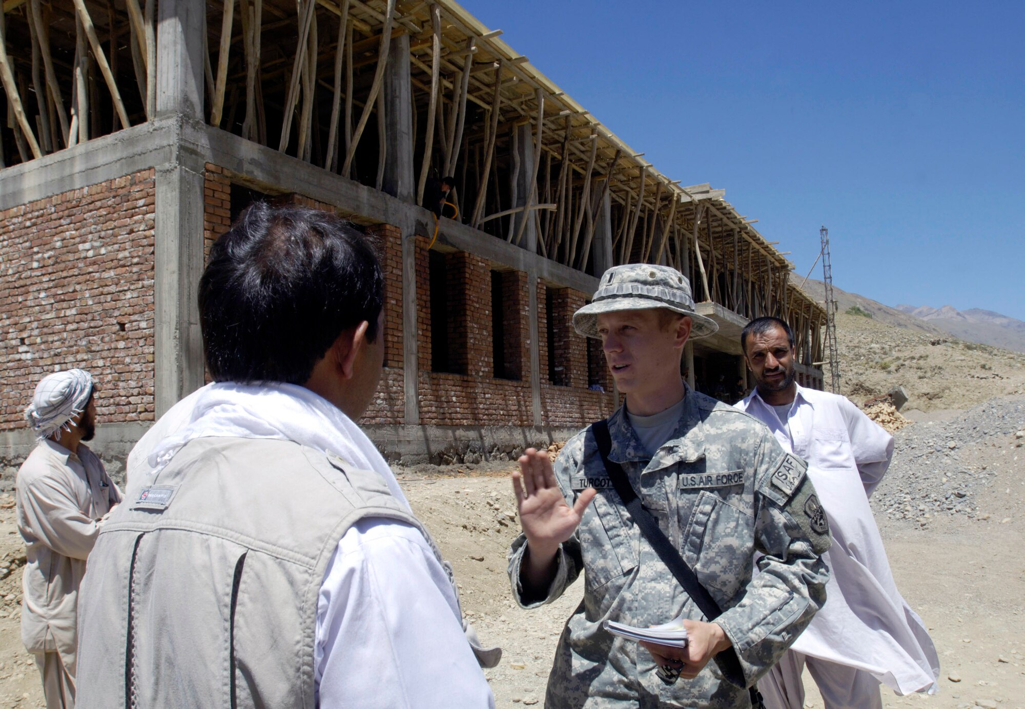 First Lt. Lee Turcotte discusses the progress of a school construction project with the contractor Aug. 4 in the Paryan district of Panjshir Province, Afghanistan.  Lieutenant Turcotte, a civil engineer from McGuire Air Force Base, N.J., is a member of the Panjshir Provincial Reconstruction Team. The school project is one of several being monitored by the PRT.  Once completed the school will accommodate children from several villages in the province. The children are currently attending classes in makeshift tents overlooking the construction site. (U.S. Air Force photo/Master Sgt. Jim Varhegyi)