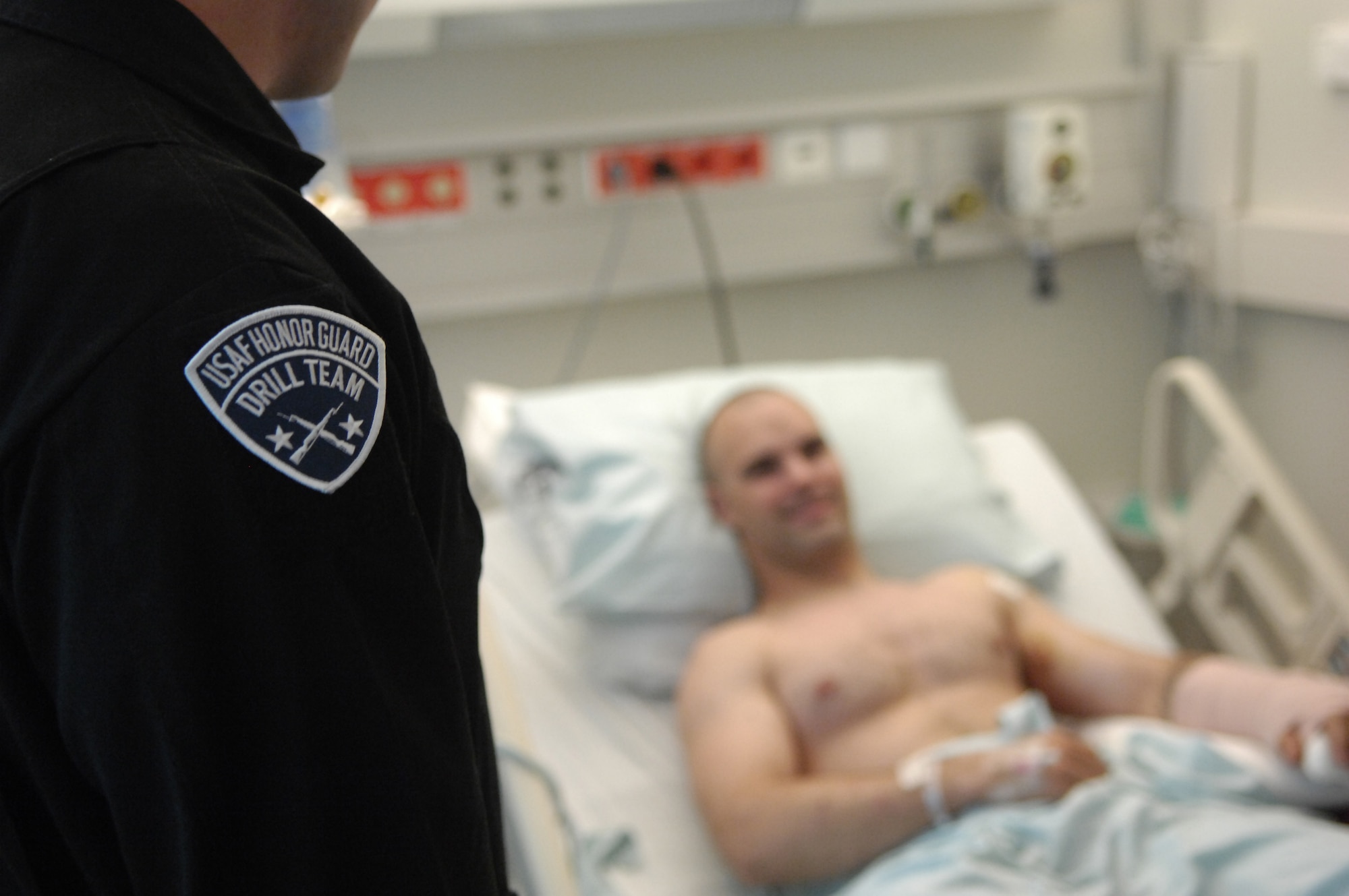 Senior Airman James Cashwell, U.S. Air Force Honor Guard Drill Team member, talks with an old friend, Army Spc. Matthew Goodwin, after a surprise meeting at Laundsthul Medical Center in Germany Aug. 1. The drill team performed for patients and hospital staff before going room to room to visit with some of America’s injured heroes. (U.S. Air Force photo by Senior Airman Daniel DeCook)