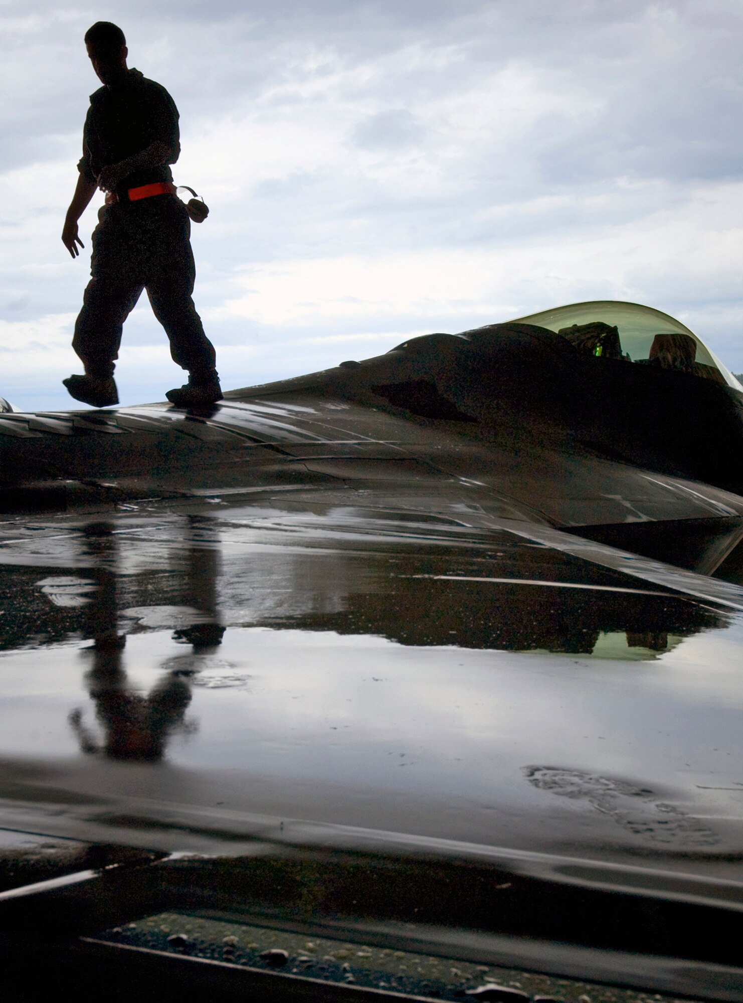 Senior Airman Brandon Fontaine walks on an F-22 Raptor wing removing tape used to prevent water from entering vents during washing Aug. 14 at Elmendorf Air Force Base, Alaska. The 90th Fighter Squadron aircraft was detailed for the first time Aug. 14 since arriving to Elmendorf AFB Aug. 8. Airman Fontaine is assigned to the 3rd Aircraft Maintenance Squadron. (U.S. Air Force photo/Senior Airman Garrett Hothan) 
