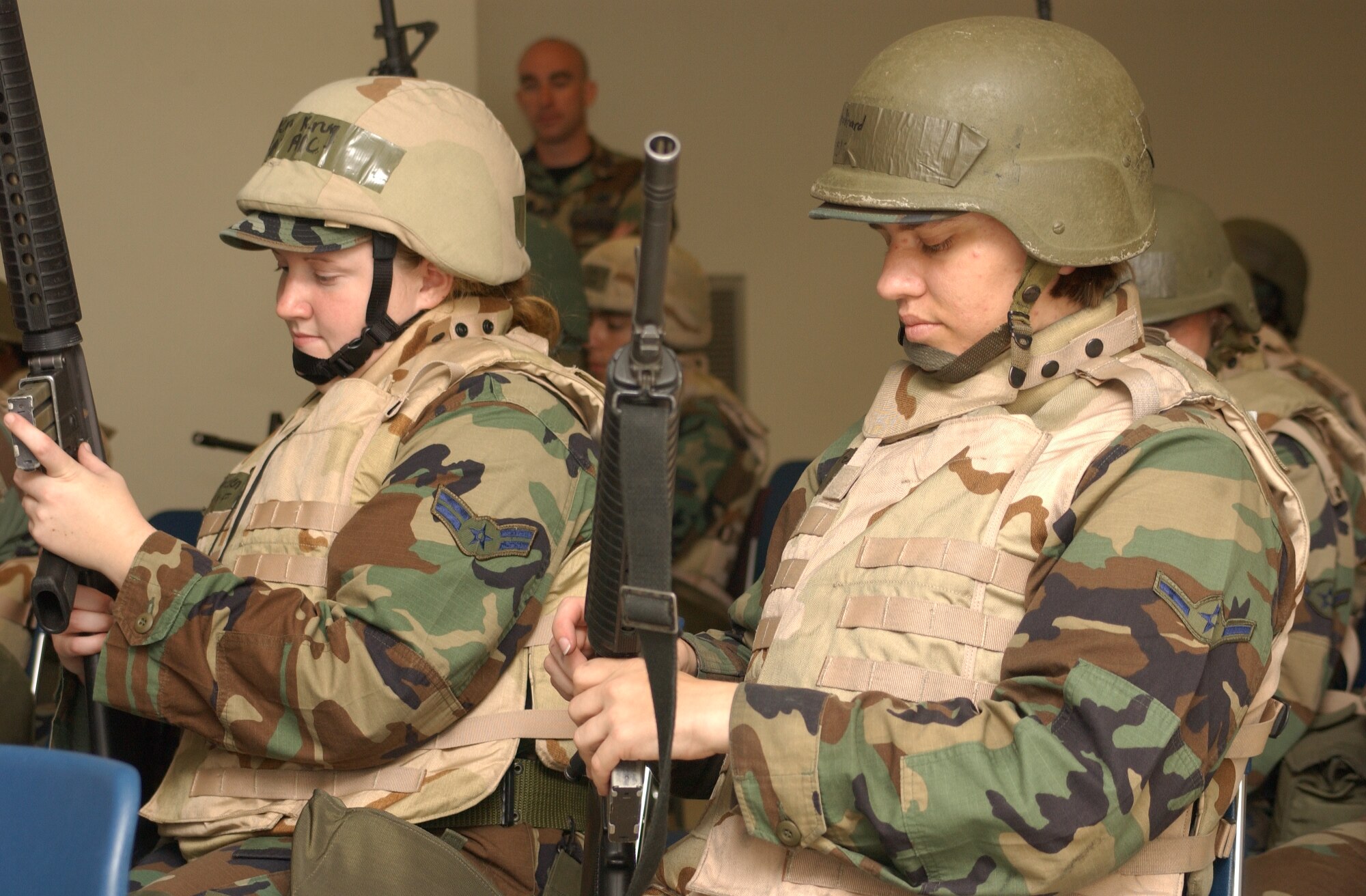 Airman 1st Class Helen Krug, left, 81st Training Group, and Airman Andrea Polinard, 81st Mission Support Squadron, familiarize themselves with handling an M-16 weapon during a field exercise Aug. 13.  The exercise tested the ability of Airmen to survive and operate under hostile circumstances, as well as self-aid and buddy care techniques.  (U.S. Air Force photo by Kemberly Groue)