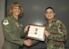 Col. Margaret Woodward, 89th Airlift Wing commander, presents an award citation after pining a Legion of Merit Medal to the collar of Senior Airman Joseph Vasquez. Airman Vasquez is assigned to the 89th Communications Squadron as a radio operator. The Legion of Merit is an award, which is given for service rendered in a clearly exceptional manner. 
