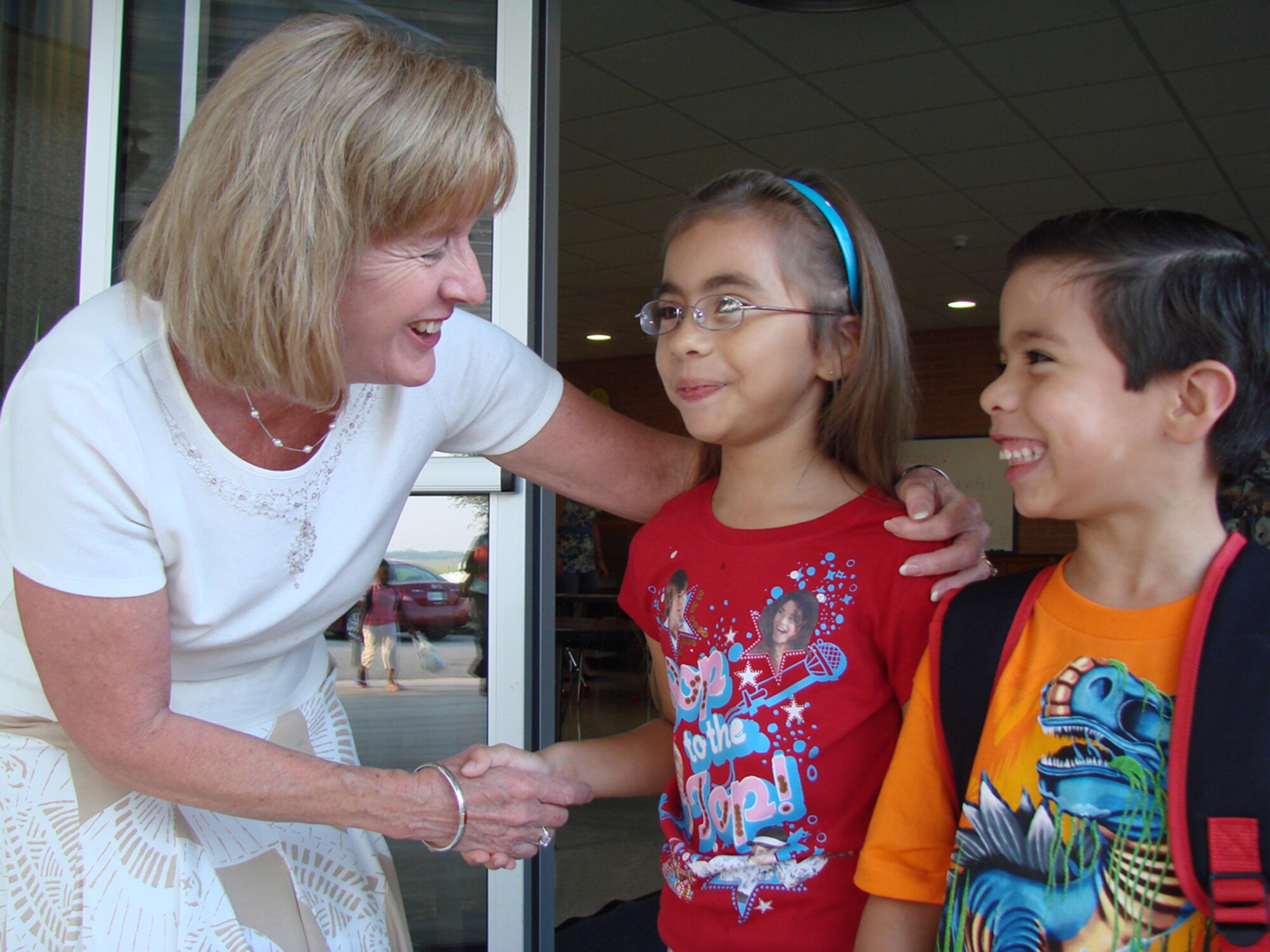Eisenhower Elementary School Principal Polly Maxwell greets students Serena and Robert Rodriguez, children of Tech. Sgt. Robert and Brenda Rodriguez, on the first day of school Thursday. Mrs. Maxwell is the 71st Mission Support Group's honorary commander. (U.S. Air Force photo by Tech. Sgt. Mary Davis)              