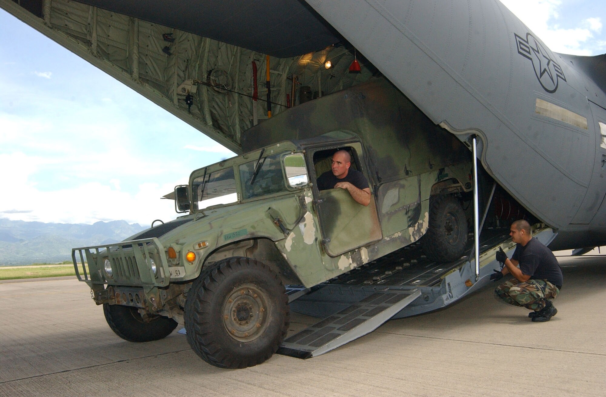Senior Airman Jason Caswell backs a Humvee inside a C-130 Hercules Aug. 17  at Soto Cano Air Base, Honduras, while Staff Sgt. Andre Talltree checks for clearance. The Humvee is being deployed to Peru along with a mobile surgical team from Soto Cano.  Approximately 30 Soldiers and Airmen are responding to the Aug. 15 earthquake in Peru and are taking 4,470 pounds of medical supplies for relief efforts.  Airman Caswell and Sergeant Talltree are assigned to the 612th Air Base Squadron at Soto Cano AB. (U.S. Air Force photo/ Tech. Sgt. Sonny Cohrs) 