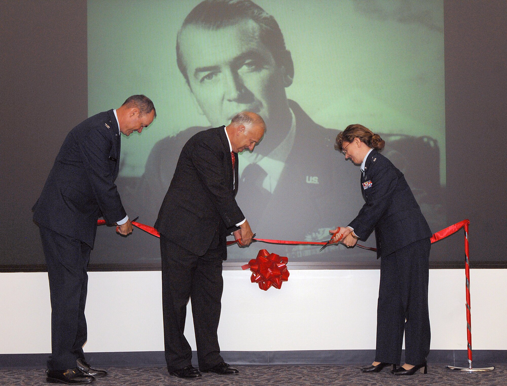 Col. Terry Ross (left), Carson Green and Lt. Col. Diane Jones cut the ribbon at the Jimmy Stewart Theater Dedication Ceremony Aug. 13 at Building 52 on Bolling Air Force Base, D.C. The theater is named after Brig. Gen. James Stewart who enlisted in the Army Air Corps in 1941 and rose to the rank of colonel in four years. At the time of his enlistment, Mr. Stewart was a famous actor with an Academy Award to his name. Colonel Ross is the 11th Wing vice commander, Mr. Green is the president of the Jimmy Maitland Stewart Museum, and Colonel Jones is the 11th Mission Support Squadron commander. (U.S. Air Force photo/Airman 1st Class Tim Chacon)