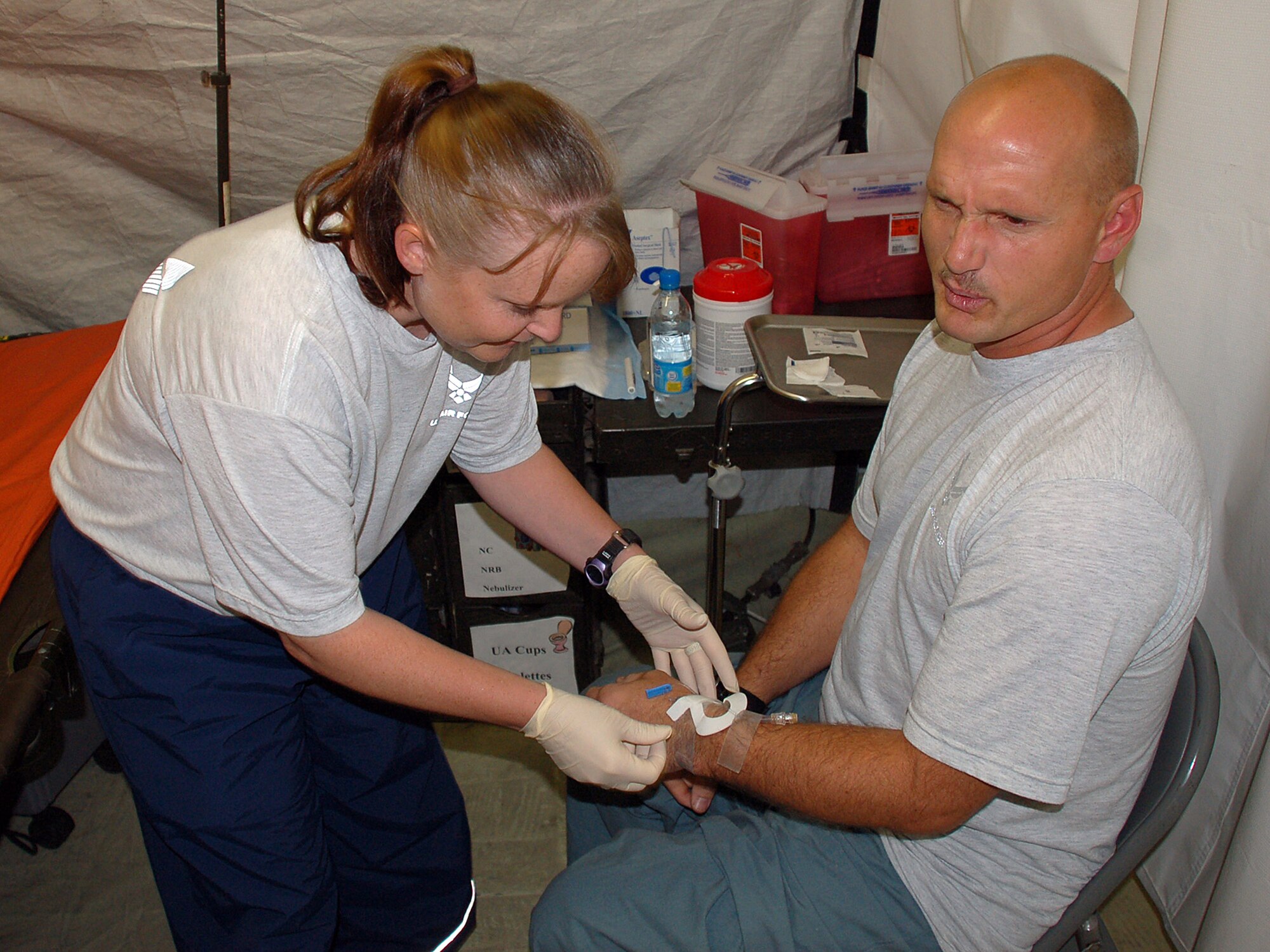 Tech. Sgt. Michelle Cools removes the IV from Tech. Sgt. Charles Bean's wrist before he is able to check out of the clinic July 28 at Manas Air Base, Kyrgyzstan. Sergeant Cools is a 376th Expeditionary Medical Group medical technician, and Sergeant Bean had to have surgery for appendicitis. (U.S. Air Force photo/Staff Sgt. Les Waters) 
