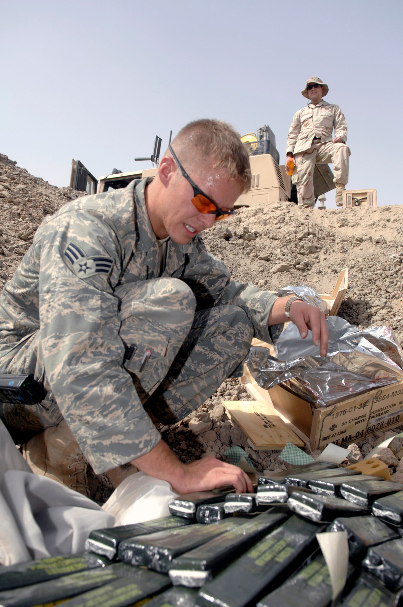 Staff Sgt. Anthony Pousen observes as Senior Airman Jonathan Sheridan prepares C-4 explosives Aug. 10 at Ali Air Base, Iraq, for a controlled detonation of confiscated weapons. The Airmen are assigned to the 407th Civil Engineer Squadron's explosive ordnance disposal team. The team disposes of confiscated weapons and unexploded ordnance and trains convoy people to recognize improvised explosive devices. (U.S. Air Force photo/Master Sgt. Robert Valenca) 