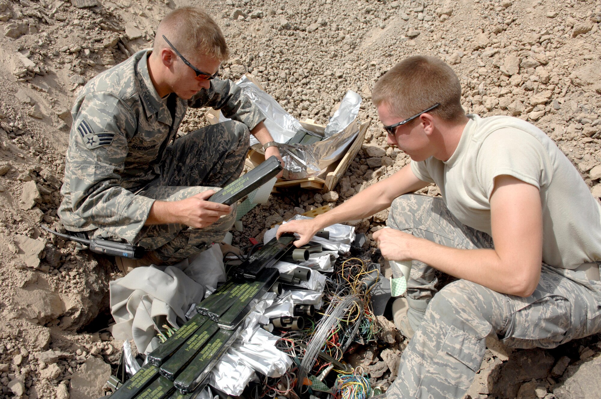 Senior Airmen Jonathan Sheridan (left) and Aaron Carroll prepare C-4 explosives Aug. 10 at Ali Air Base, Iraq, for a controlled detonation of confiscated weapons.  The Airmen are assigned to the 407th Civil Engineer Squadron's explosive ordnance disposal team. The team disposes of confiscated weapons and unexploded ordnance and trains convoy people to recognize improvised explosive devices. (U.S. Air Force photo/Master Sgt. Robert Valenca) 
