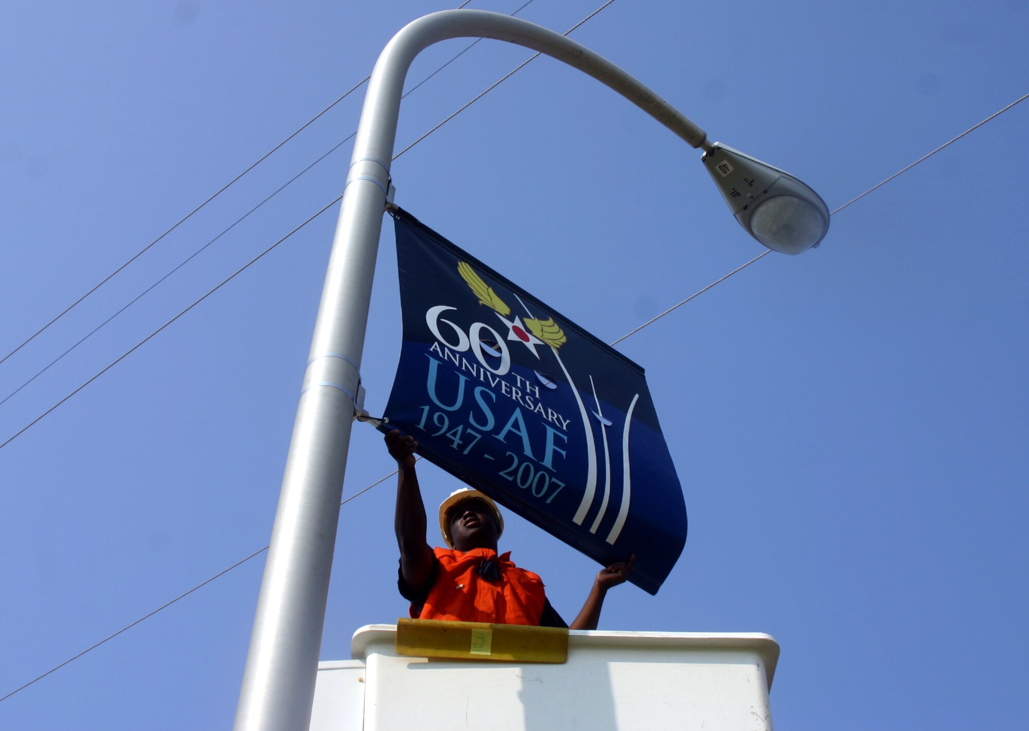 Airman 1st Class DeAndreas Crawford, an electrical journeyman with the 82nd Civil Engineer Squadron, attaches an Air Force 60th Anniversary banner to a streetlamp near the main gate.  The banners are hung all over the base in advertisement of the upcoming milestone.  (U.S. Air Force photo/Staff Sgt. Tonnette Thompson)