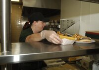 MINOT AIR FORCE BASE, N.D. -- Beverly Vajda, Kelley’s Place service worker, serves up a hamburger and fries at newly renovated Kelley’s Place here Aug. 15. The $170,000 renovation project started in June and gave Kelley’s Place a brand new front counter, new menu board, state-of-the-art beverage counter and all new equipment in the kitchen. The renovations also gave Kelley’s Place the ability to offer pizza, milkshakes and malts. (U.S. Air Force photo by Senior Airman Stacey Moless)
