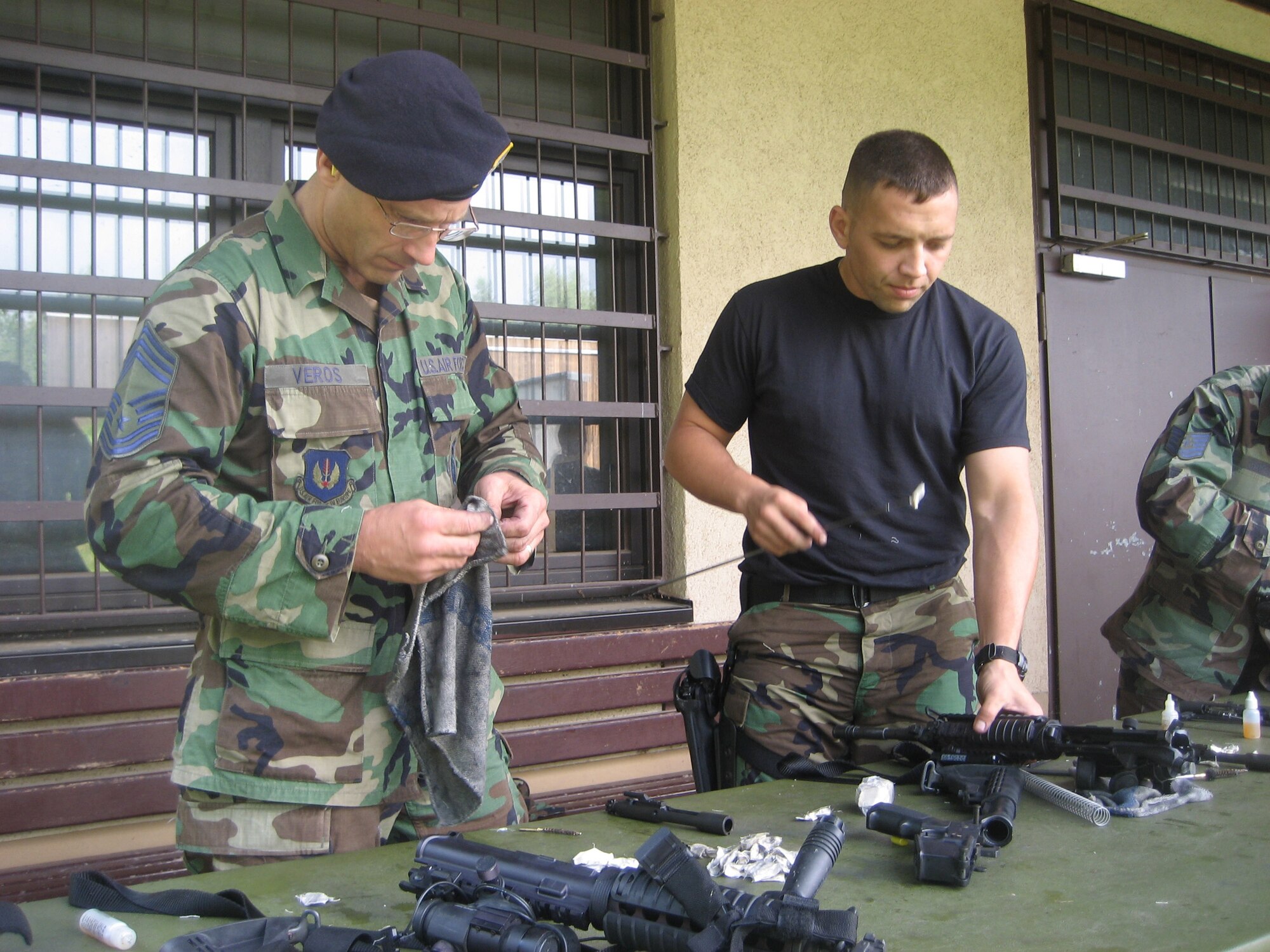 SPANGDAHLEM AIR BASE, Germany – Chief Master Sgt. Michael Veros and Capt. Jesse Goens, 52nd Security Forces Squadron, clean their weapons after completing weapons qualification at Baumholder Range, Germany, Aug. 16. More than 30 Airmen from Spangdahlem AB conducted weapons training at the range. (U.S. Air Force photo/Staff Sgt. Andrea Knudson)         