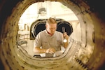 Dave Duggar, quality assurance engine inspector, checks the boat tail of a T-38 Tuesday. (Photo by Don Lindsey)