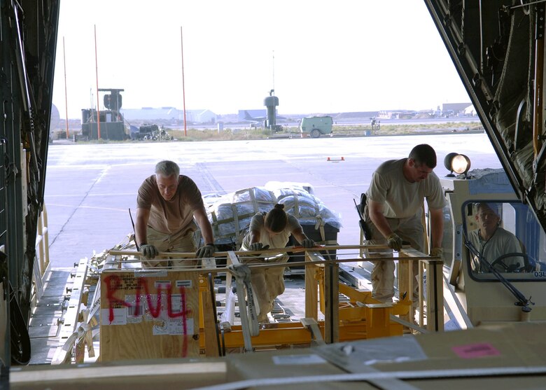 Senior Airman Sarah Hansen (middle), 67th Expeditionary Aerial Port Squadron, helps other members of her squadron push pallets from the loader into the cargo area of a C-130. Airman Hansen is a reservist deployed from Hill Air Force Base, Utah. (U.S. Air Force photo by Staff Sgt. Craig Seals)