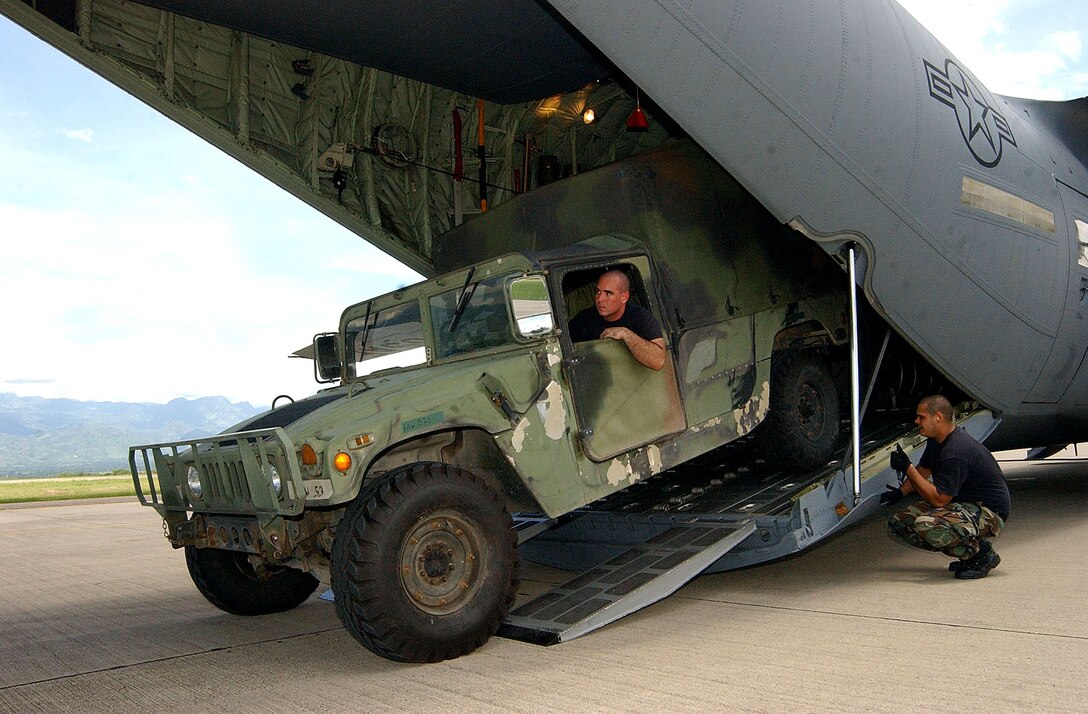 Senior Airman Jason Caswell drives a high humvee  inside a C-130J aircraft while Staff Sgt. Andre Talltree checks for clearance on Soto Cano Air Base, Honduras, Aug. 17, 2007.  They are with 612th Air Base Squadron. The vehicle is being deployed to Peru to support a humanitarian relief mission in the wake of an Aug. 15 earthquake, along with a Mobile Surgical Team from Soto Cano.