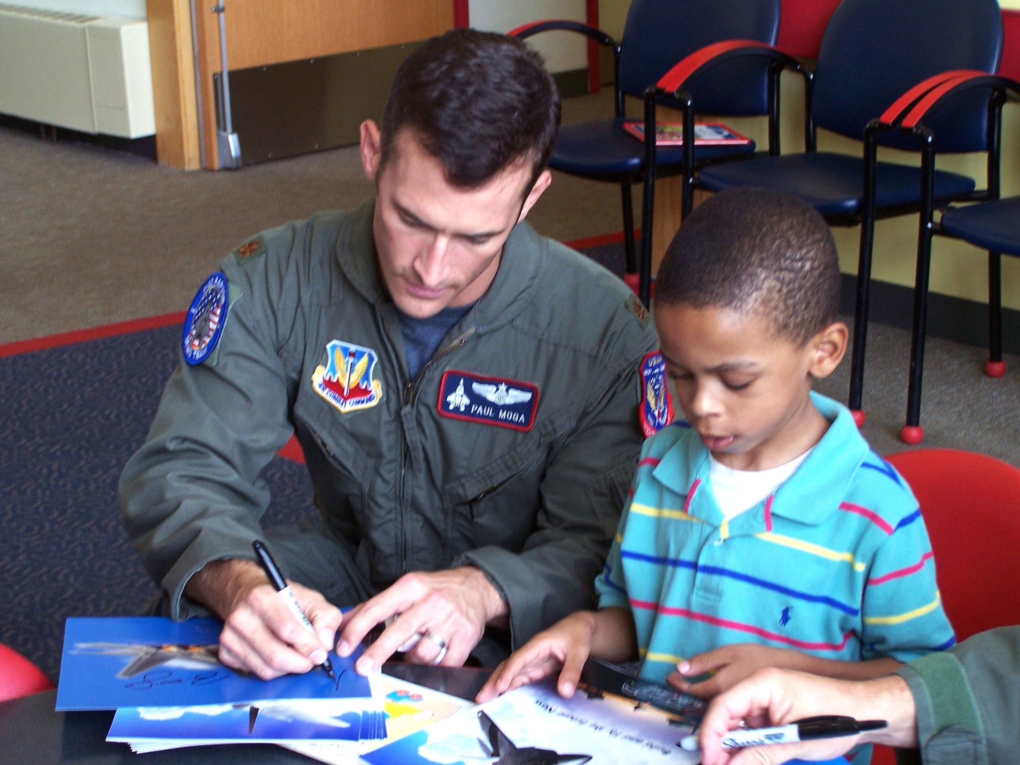Maj. Paul Moga, the Air Force's sole F-22 Raptor demonstration pilot, signs an autograph for La Rabida Children's Hospital patient Maseeh Muhammad Aug. 15 during their visit in support of the Chicago Air and Water Show. (U.S. Air Force photo/Capt. Rob Lazaro)
