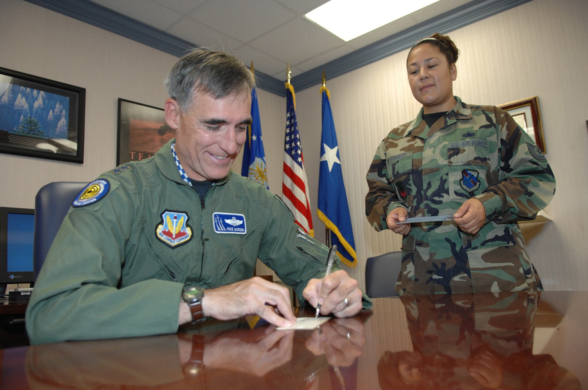 Major Gen. R. Michael Worden, United States Air Force Warfare Center commander, signs a check for his 60th Anniversary Air Force Ball ticket, which is being given to him by Tech. Sgt. Christy Stanley, 99th Logistics Readiness Squadron, and the point of contact for the Air Force Ball ticket sales at Nellis.
(U.S. Air Force Photo by Senior Airman Larry E. Reid Jr.)