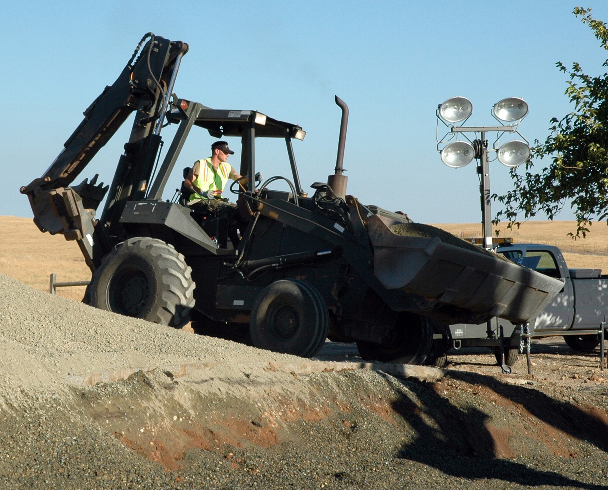 Senior Amn Andrew Copeland, a heavy equipment journeyman for the 940th Civil Engineer Squadron, Beale Air Force Base, Calif., uses a combination front end loader/back hoe to help fill in and build up a road bed Aug 11. A team of ten Reservists worked alongside their active duty counterparts from the 9th CES to complete road repairs over a weekend. The work also provided training necessary to prepare these Citizen Warriors for deployments in support of the Global War on Terror. (US Air Force photo/Master Sgt Ellen L Hatfield)