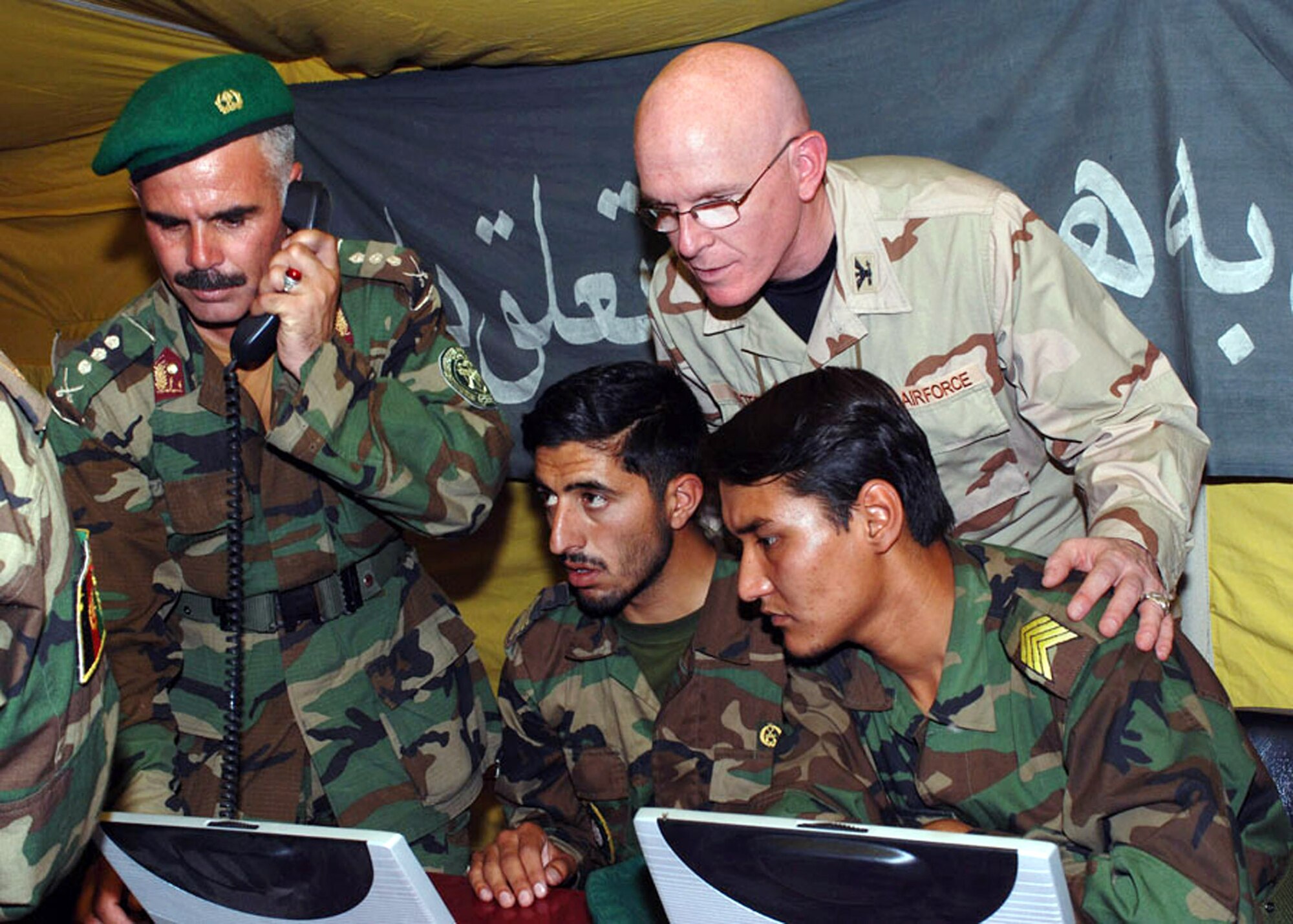 Col. Christopher Cotts watches while two Afghan soldiers demonstrate field connectivity to the Internet during the Afghan National Army's communications conference in Kabul, Afghanistan. Colonel Cotts is director of communications for the Combined Security Transition Command-Afghanistan. (U.S. Navy photo/Petty Officer 1st Class David M. Votroubek) 
