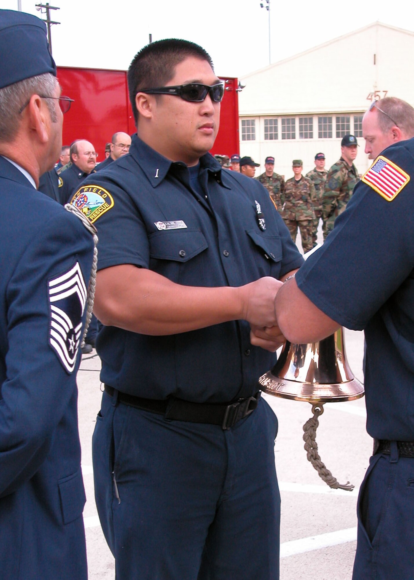 As fellow firefighters look on, Kalani Ching, a Fire Engineer with the 452nd Fire Emergency Services, participates in a Ringing of the Bell ceremony that took place Sunday morning at the base flag pole. This fallen fire fighter tradition was held to honor Staff Sgt. Ricardo Villalobos who died of a motorcycle accident Saturday. (U.S. Air Force photo by Capt. Caroline J. Lorimer)
