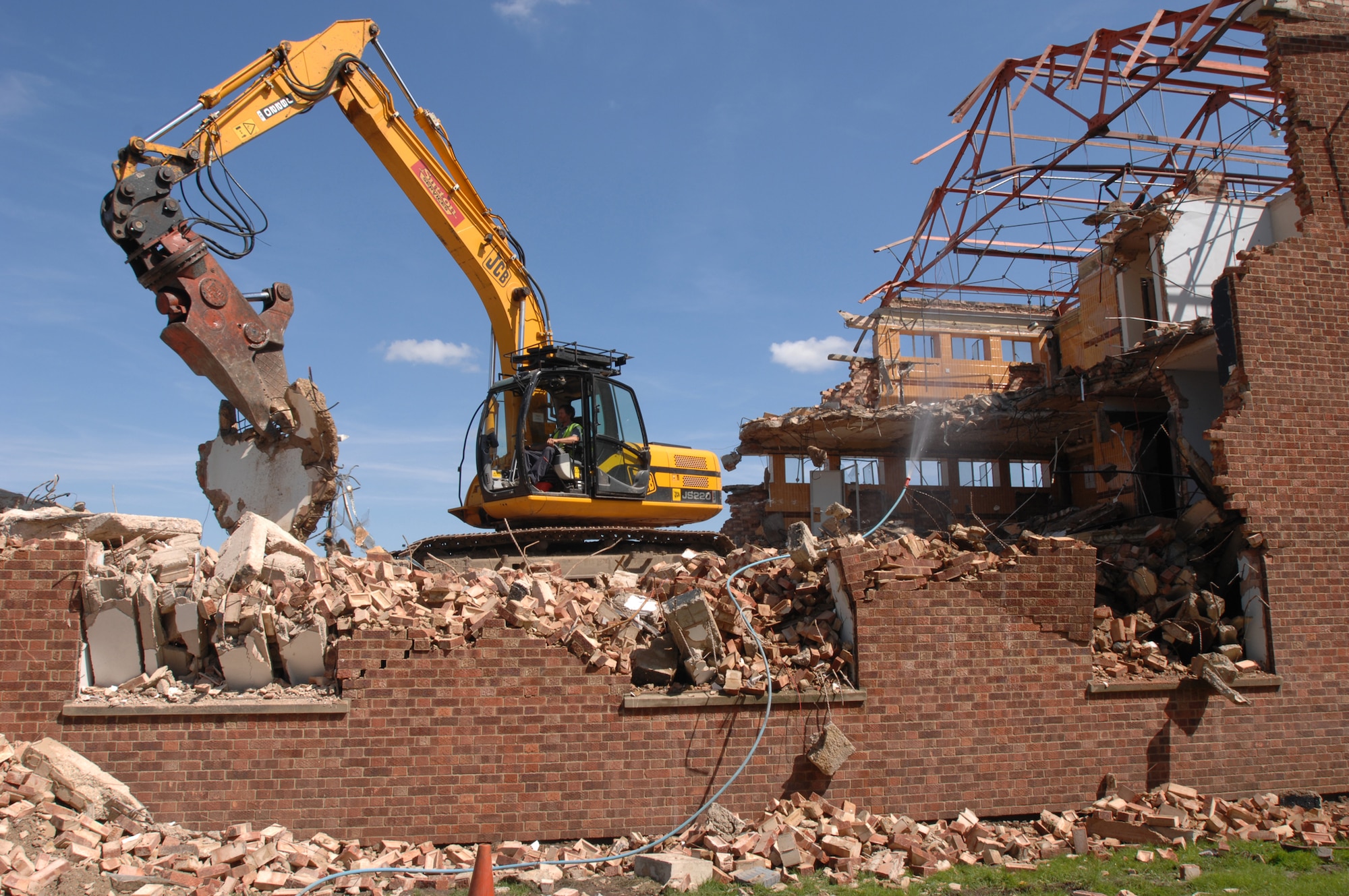 Site foreman Robert Saunders, manning a JS 220/360 degree excavator, sorts the rubble of Building 402 into separate piles of concrete and scrap metal, Aug. 10, 2007. The contractor is responsible for removing the rubble and sorted materials from the base. The unusable pieces will be crushed and recycled for future building materials.  (U.S. Air Force photo by Tech. Sgt. Tracy L. DeMarco)