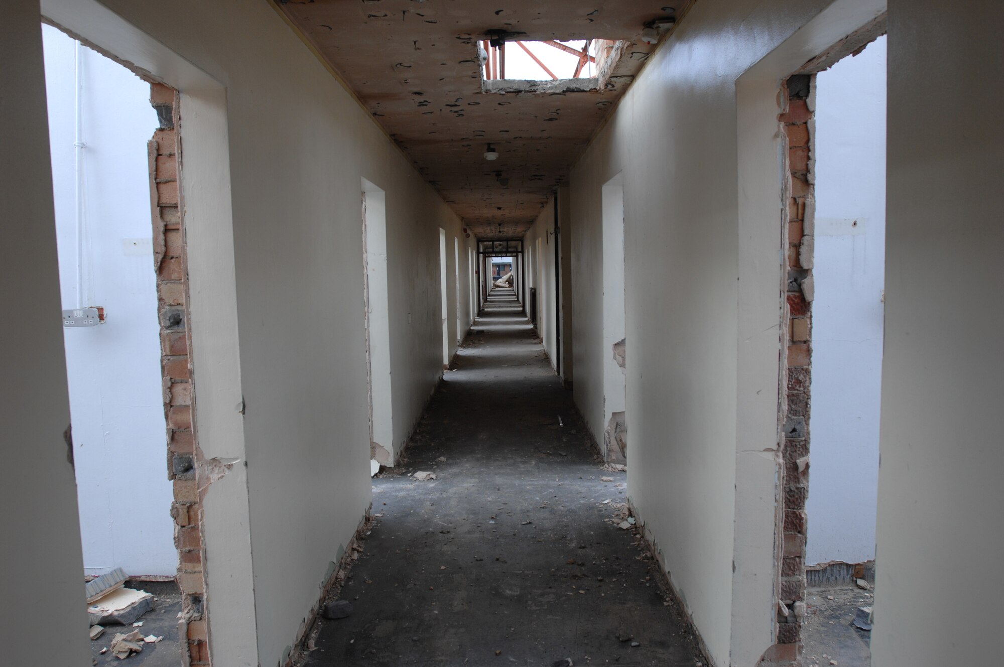Building 402, after being soft stripped, which involves removing all wood and carpet, stands primed for demolition, Aug. 9, 2007. Once used as visiting quarters, Building 402 will be replaced by a plot of grass once the rubble is removed. The 15-week project is part of the base General Plan to create a campus-like appearance near the Airmen dormitories. (U.S. Air Force photo by Tech. Sgt. Tracy L. DeMarco)