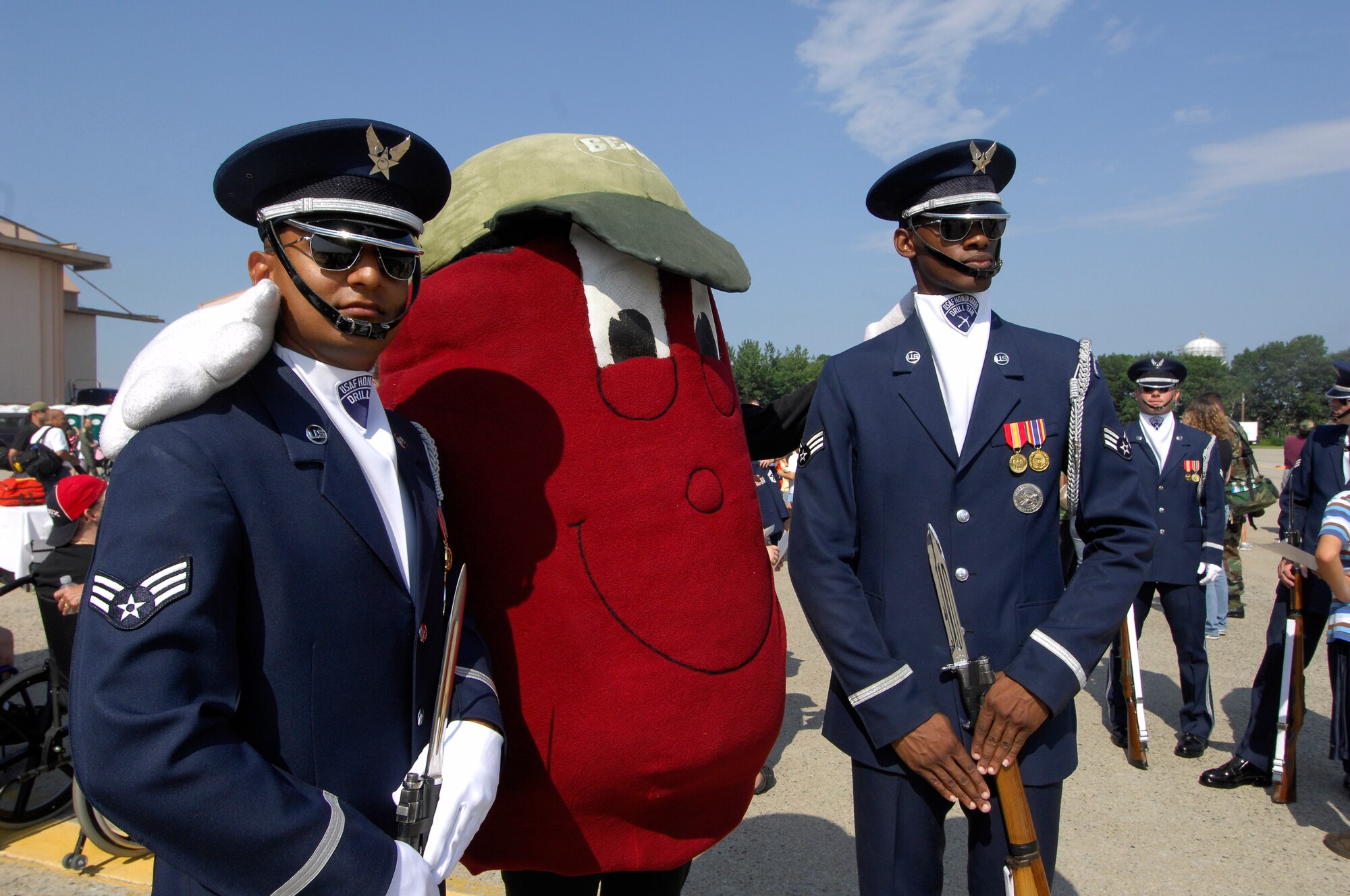 Senior Airmen Jermaine James and David Perry, Drill Team members, pose with the Boston Baked Bean mascot while spending time with kids from the New England Make-a-Wish foundation.  The Drill Team performed for the kids at an invite-only event the day before the Wings of Hope Air Show at Pease ANGB, NH.  (U.S. Air Force photo by Airmen 1st Class Alexandre Montes)(Released)