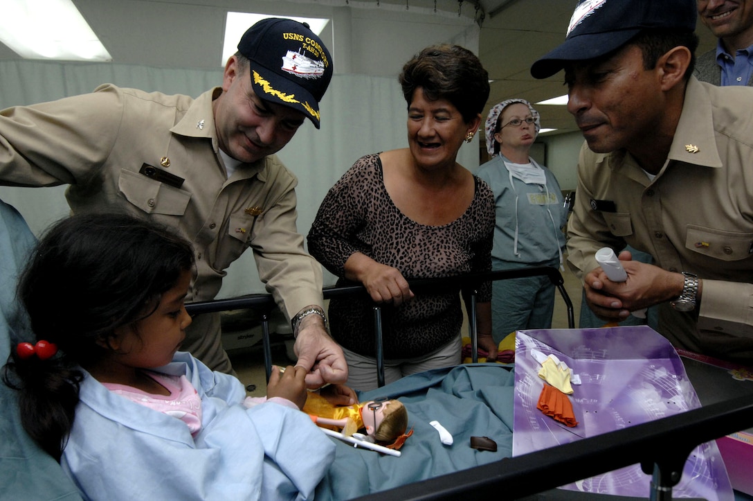 U.S. Navy Capt. Bob Kapcio, hospital ship USNS Comfort mission commander, and Lt. Cmdr Manny Santiago, Comfort's casualty and receiving division officer, visit with a patient during a port visit to Manta, Ecuador, Aug. 17, 2007. Comfort is on a four-month humanitarian deployment to Latin America and the Caribbean providing medical treatment to patients in a dozen countries. 