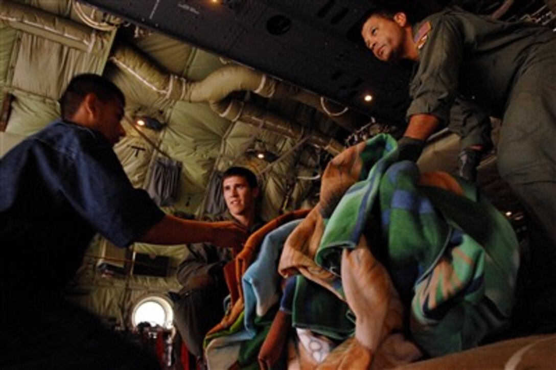 U.S. Air Force Tech. Sgt. Will Morales (right) and Senior Airman Brandon Krantz, both loadmasters from the Maryland Air National Guard, help Peruvian aid workers unload blankets from a C-130 Hercules aircraft in Pisco, Peru, on Aug. 18, 2007.  In addition to transporting the relief supplies, the Department of Defense has deployed a 30-person mobile surgical team from Joint Task Force-Bravo at Soto Cano Air Base, Honduras, and a 14-person U.S. Air Force medical team from Goodfellow Air Force Base, Texas, to Peru to provide aid to victims of the 8.0 magnitude earthquake that struck Western Peru on Aug. 15th.† U.S. Southern Command has purchased $50,000 in medical supplies that will be donated to Peruvian Ministry of Health officials.  