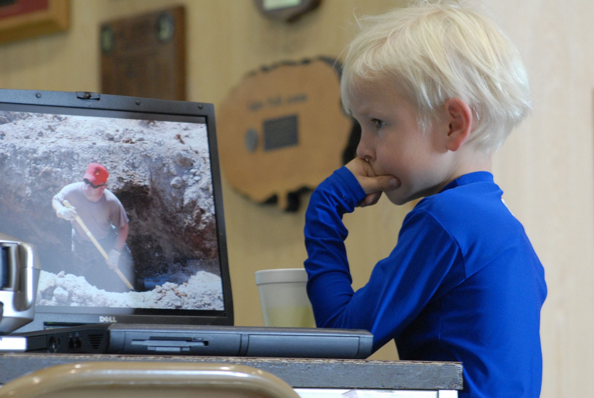 LIttle Warrior Nick, 7, intently watches a laptop that is connected to a projector running continuous slide show of RED HORSE members in action and on the job, during the 819th RED HORSE Squadron's 10th anniversary celebration Aug. 17. The squadron hosted a variety of commemorative events Aug. 15 to 18 at Malmstrom Air Force Base, Mont. (U.S. Air Force photo/John Turner).