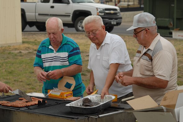 Volunteers Ken Croscutt, Steve Kubick and Bob Charpentier, work the hamburger and hot dog grill during the 819th RED HORSE Squadron's 10th anniversary celebration Aug. 17. The squadron hosted a variety of commemorative events Aug. 15 to 18 at Malmstrom Air Force Base, Mont. (U.S. Air Force photo/John Turner).