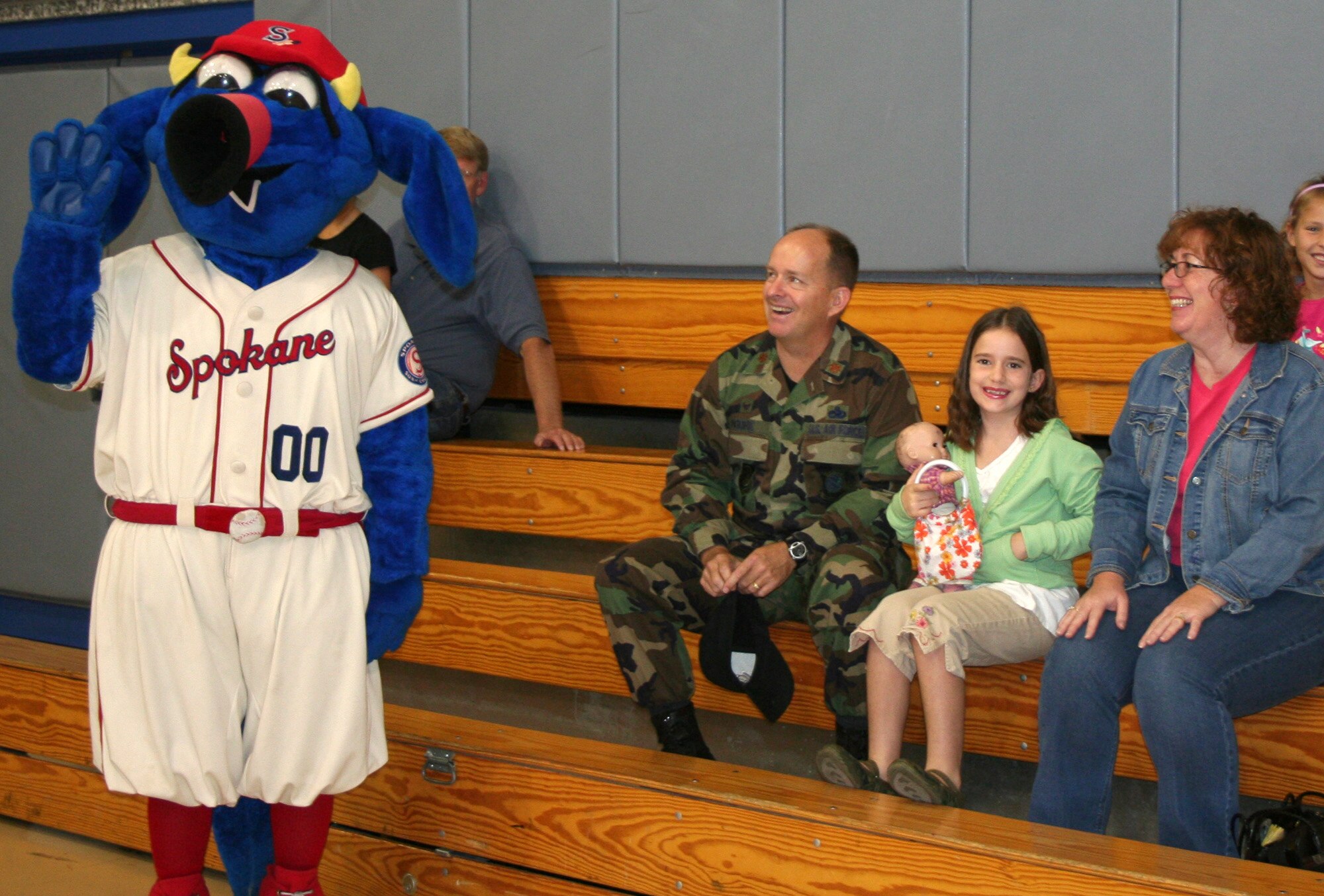 FAIRCHILD AIR FORCE BASE, Wash. – Mallory Moore, the Air Mobility Command FitFactor winner for the month of July, and her parents Maj. Robert Moore, 92nd Aircraft Maintenance Squadron commander, and Jenna Moore, wait for the beginning of the FitFactor awards presentation Aug. 21 as Otto, the mascot for the Spokane Indians baseball team, gives a wave to the incoming crowd. (U.S. Air Force photo / Cara Burch)