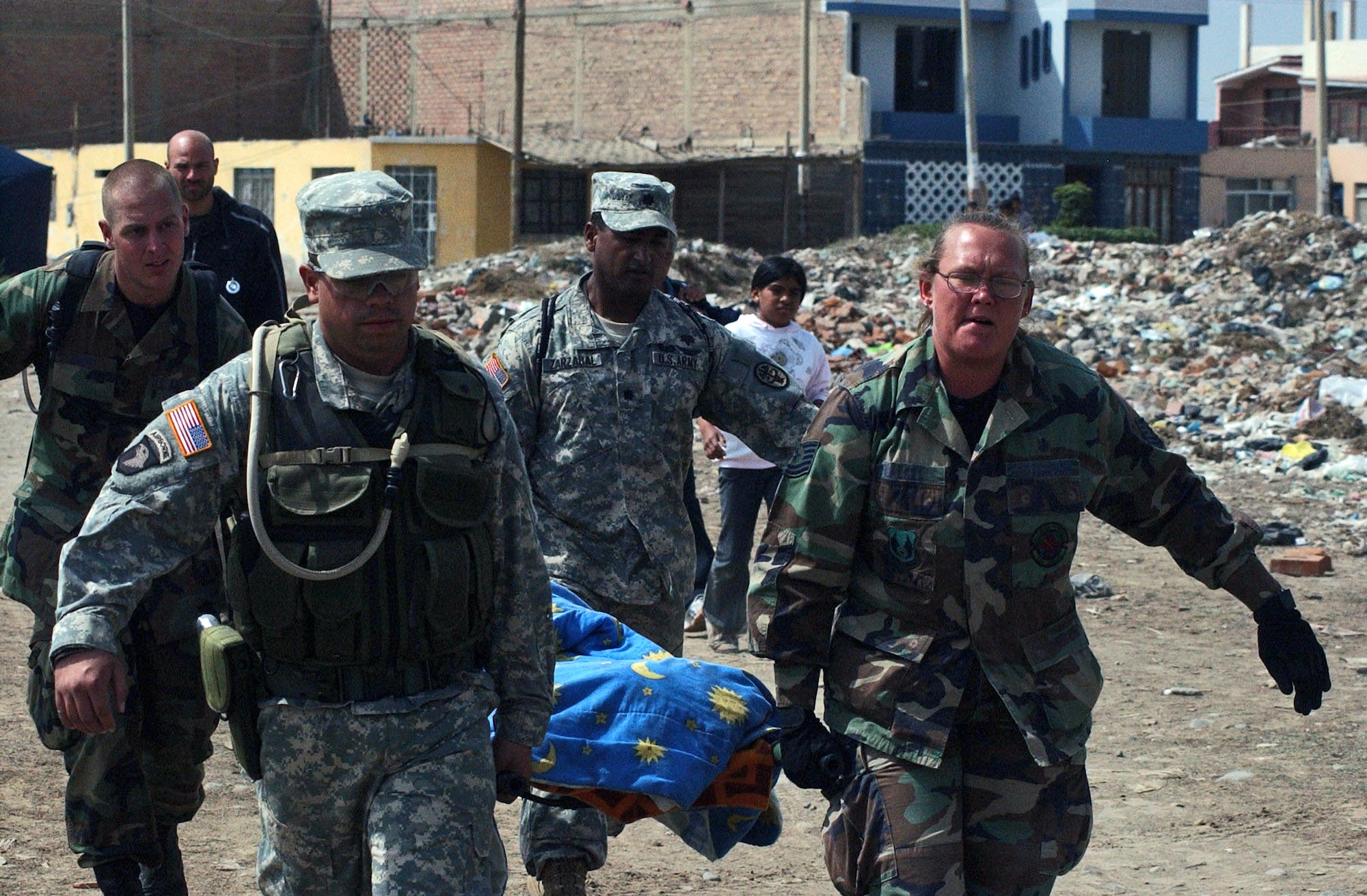 From left, Senior Airman Shaun Emery, Army Spc. Jose Hernandez, Army Lt. Col. Eduardo Zarzabal and Tech. Sgt Melissa Walker carry a woman from her home to the site of the team's medical care site Aug. 20 in Pisco, Peru. They are members of the Joint Task Force-Bravo medical humanitarian relief team deployed from Soto Cano Air Base, Honduras.  The team arrived in Peru Aug. 17 to provide medical humanitarian assistance to the citizens of Pisco following an 8.0 magnitude earthquake Aug. 15. (U.S. Army photo/Spc. Grant Vaught) 

