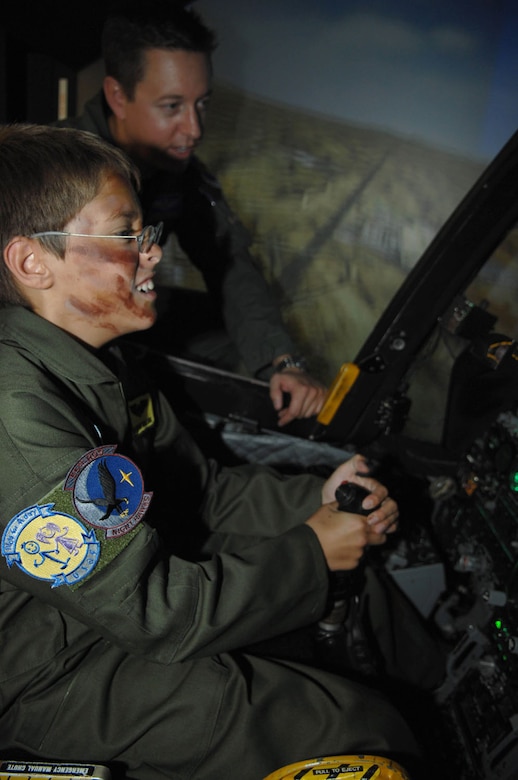 Major Chris Zentner, an A-10 Thunderbolt II pilot with the 354th Fighter Squadron helps 10-year-old Brandon Smalling in the A-10 simulator Thursday August 10 at Davis-Monthan AFB, Ariz as part of the Pilot for a Day program. The program is designed to help children with disabilities or serious illnesses to enjoy a day focused on them and their interest in aviation. Activities in the program include; trying on life support equipment, using Night Vision goggles, flying an A-10 simulator, and seeing an A-10  up close. (U.S. Air Force photo/Senior Airman Christina D. Kinsey)