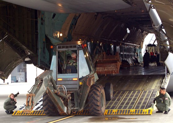 Staff Sgt. Shawna Warren, a Reserve loadmaster with the 433rd Airlift Wing, gives a thumbs up to Senior Master Sgt. Gary Hochenberger as he drives a backhoe onto an Alamo Wing C-5A. Senior Airman Ionatana Cipili and Sergeant Warren loaded eight various construction vehicles into the cargo hold of the C-5. The equipment, stored in Hawaii, is being transferred to the Washoe Tribe in Nevada as part of a Defense Reutilization and Marketing Office program to provide much needed equipment to organizations like the Washoe Tribe. Equipment is used for wildfire prevention, infastructure repair and construction and transporting the valuable machinery gives practical, realistic training to military members while they meet the needs of organizations around the country. (US Air Force Photo/ Staff Sgt. Carlos Trevino)