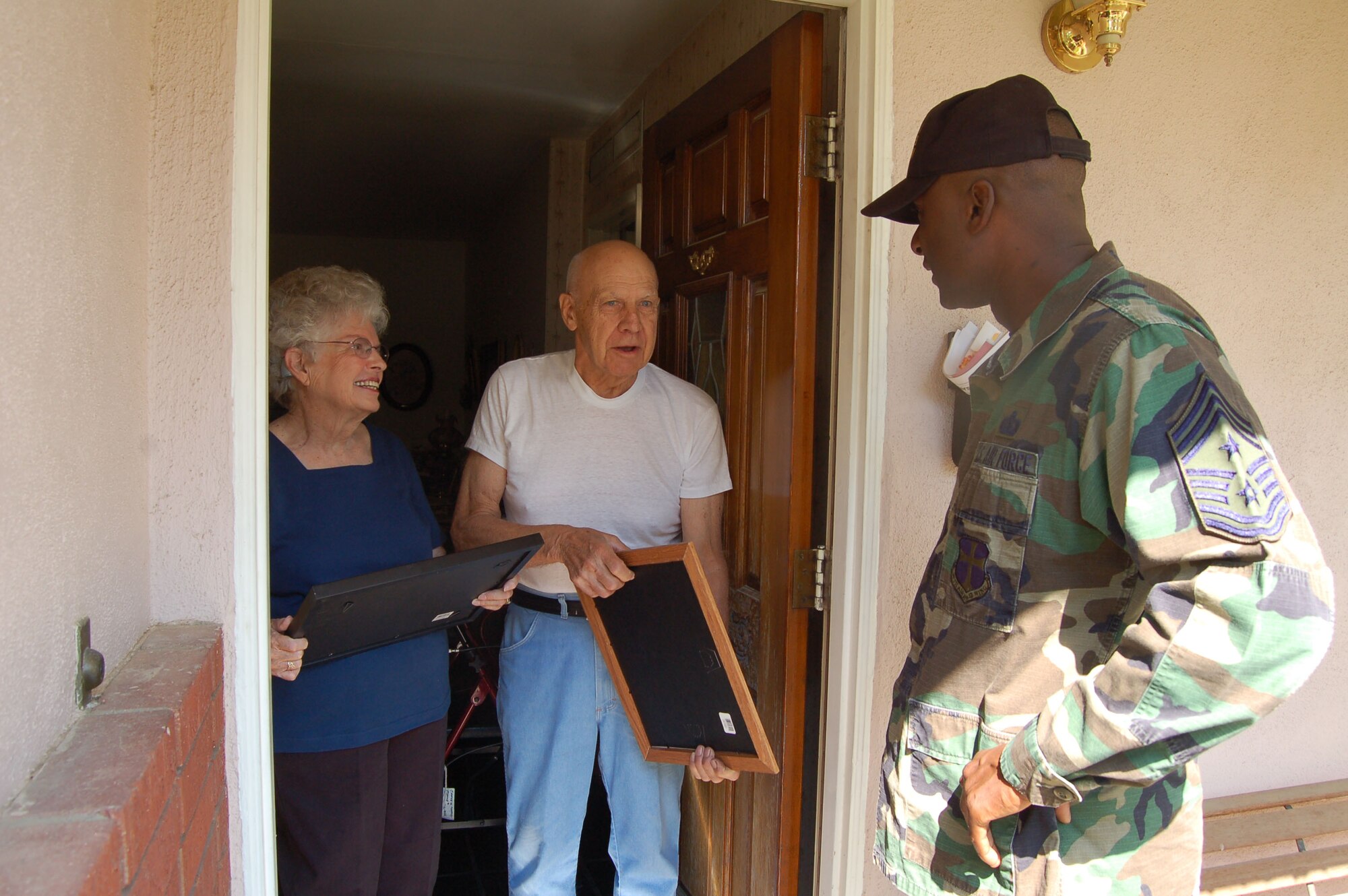 Chief Master Sgt. Juan Lewis (right), 95th Air Base Wing command chief, presented Janice and Kenneth Markey, Lancaster, Calif. residents, with a plaque on Aug 17. Chief Lewis presented the plaques on behalf of Team Edwards for the Markeys' contribution to Higher Grounds Cafe.  (Photo by Airman 1st Class Julius Delos Reyes)