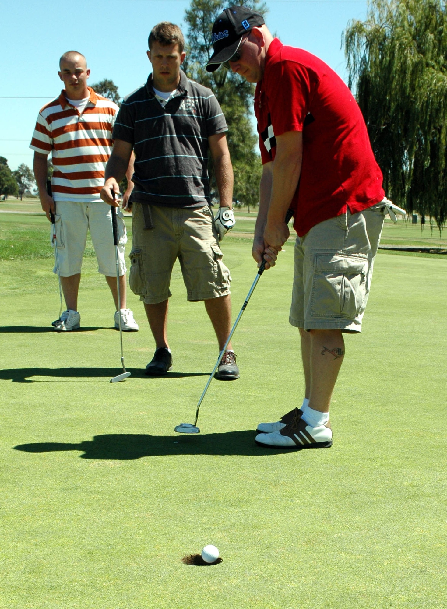 Austin Bridwell, (red shirt), along with teammates Dustin Brown, (far left), and Matthew Brattoli, watch as Bridwell sinks his birdie putt during the 60th Air Force Anniversary Golf Tournament at the Cypress Lakes Golf Course Aug. 17. The tournament was a four-man scramble format and the winning team was awarded Sky Caddie II GPS units, along with other prizes. (U.S. Air Force photo/Staff Sgt. Candy Knight)