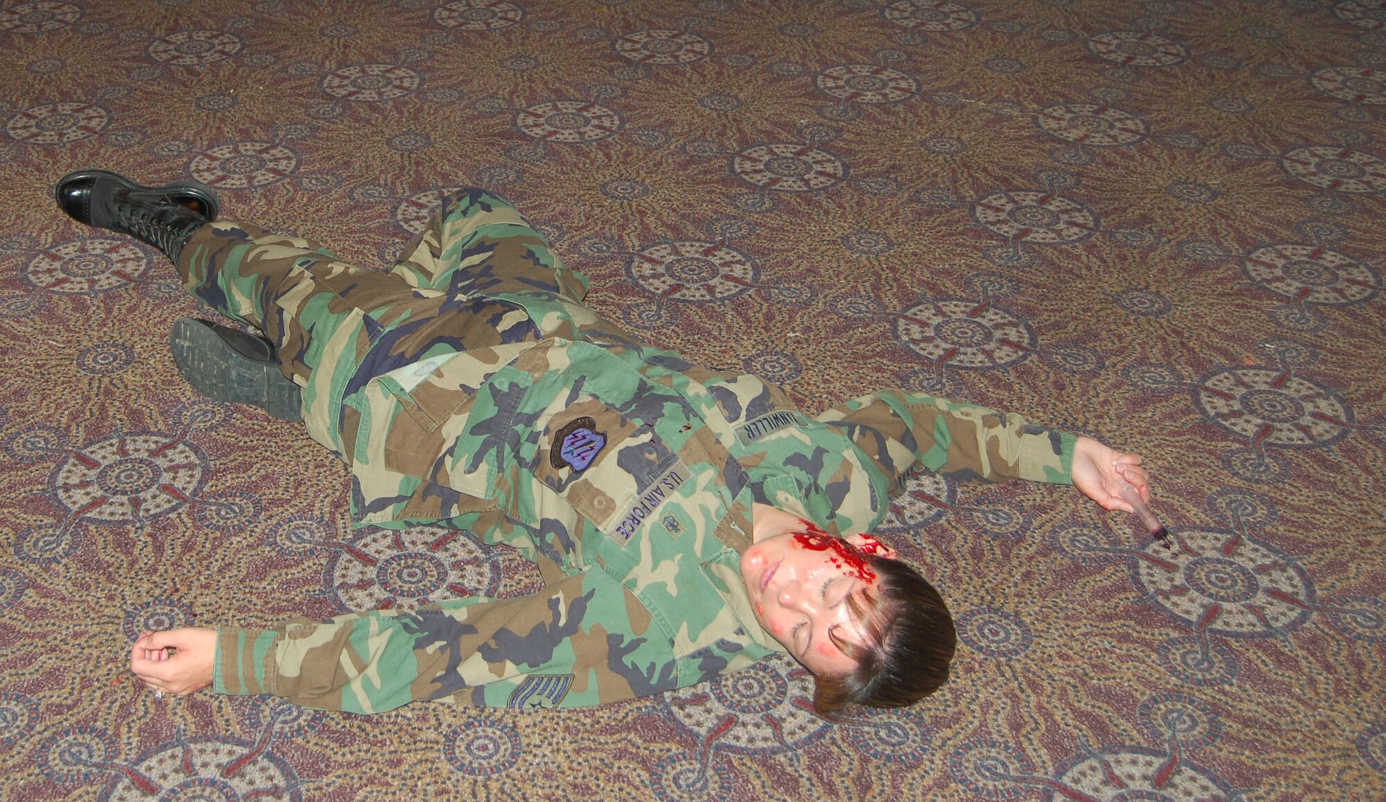 The “hostage taker” from the exercise lies mortally wounded on the base auditorium floor after the hostage situation. Moulage, make-up applied to look like an injury, was used to make the scenario as realistic as possible. (U.S. Air Force photo by Corey Dahl)