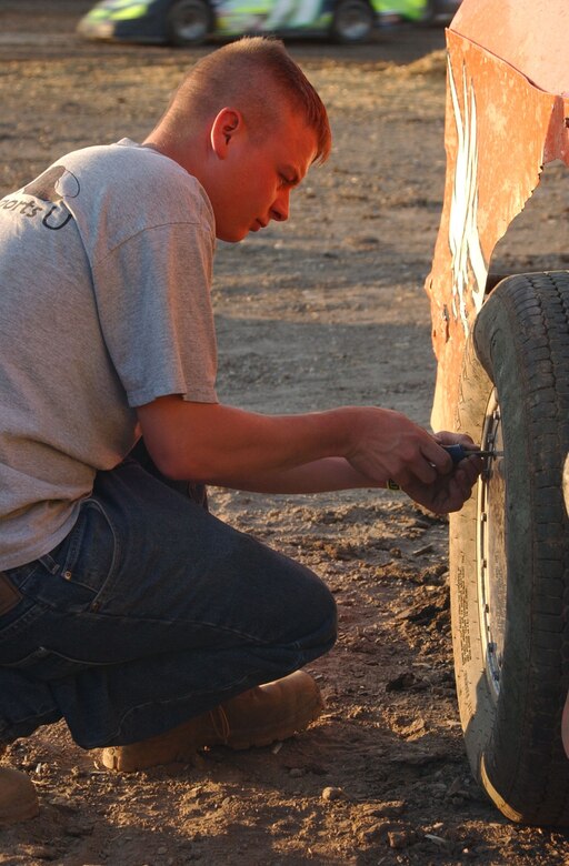 Airman 1st Class Edward Freeman, 819th RED HORSE Squadron heavy machine operator, installs a wheel cover onto the number 00 modified car owned by Master Sgt. Russell Wolfe, 341st Logistics Readiness Squadron. Several Team Malmstrom Warriors work and volunteer at the Electric City Speedway in Great Falls, Mont. (U.S. Air Force photo/Airman 1st Class Dillon White).