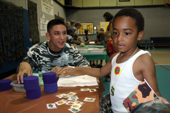 Airman 1st Class Daniel Paredes, 341st Missile Security Forces Squadron, helps Little Warrior Corey, 6, apply a washable airplane tatoo to his hand during Operation Be Our Guest Aug. 17 at the Youth Programs Center at Malmstrom Air Force Base, Mont. Operation BOG provides support to children and teaches youth about the changes in their family relationships and the stresses that can occur when a family member is deployed. (U.S. Air Force photo/Senior Airman Eydie Sakura).