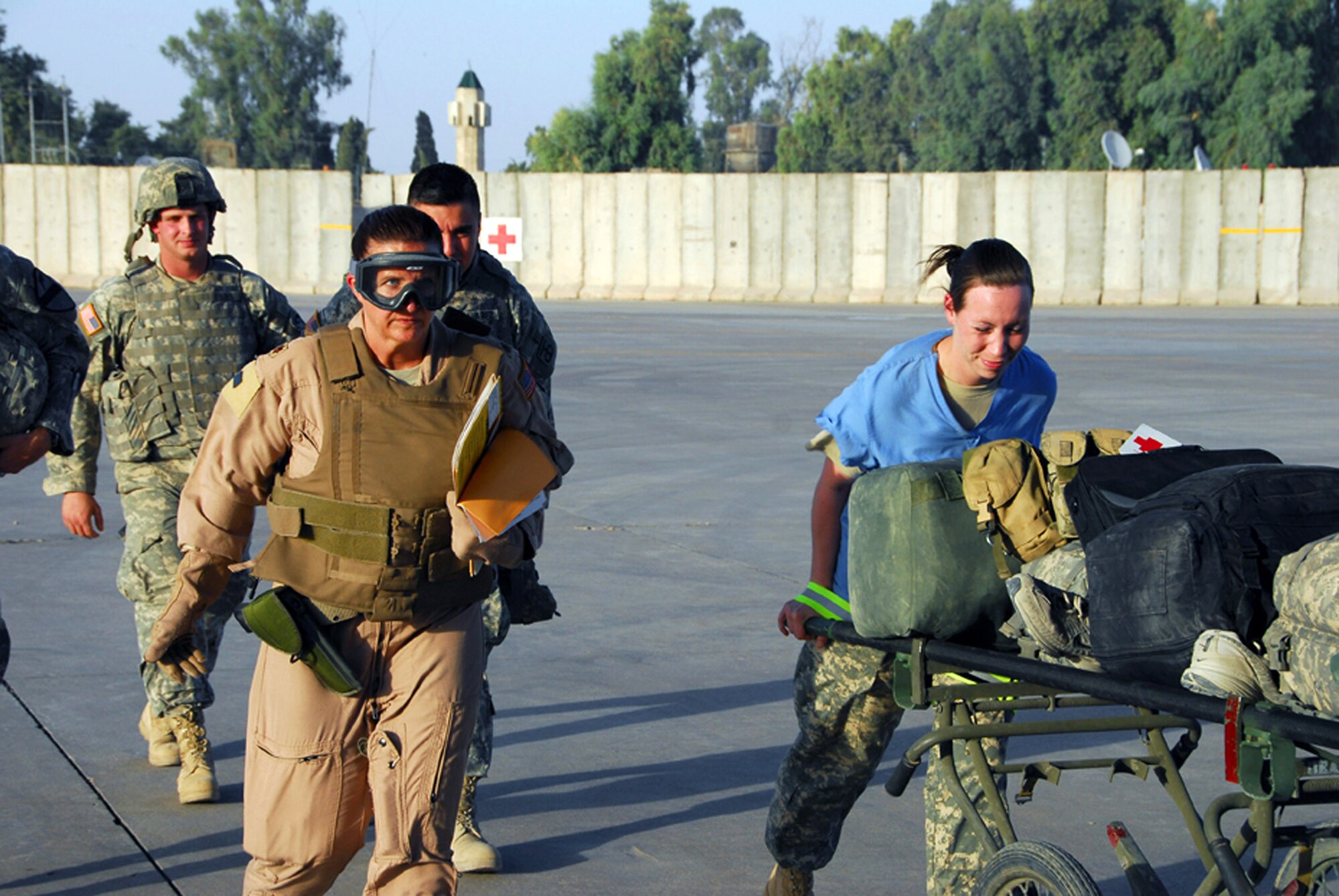 Maj. Beth Ann Gambill (carrying records) escorts wounded Soldiers across an airfield in Mosul, Iraq, Aug. 18 to an awaiting C-130 Hercules.  The aircraft will transport them to Balad Air Base, Iraq, as part of an aeromedical evacuation mission.  Major Gambill is the deputy chief of the Aeromedical Evacuation Control Team, (U.S. Air Force photo/Tech. Sgt. Scott Moorman) 