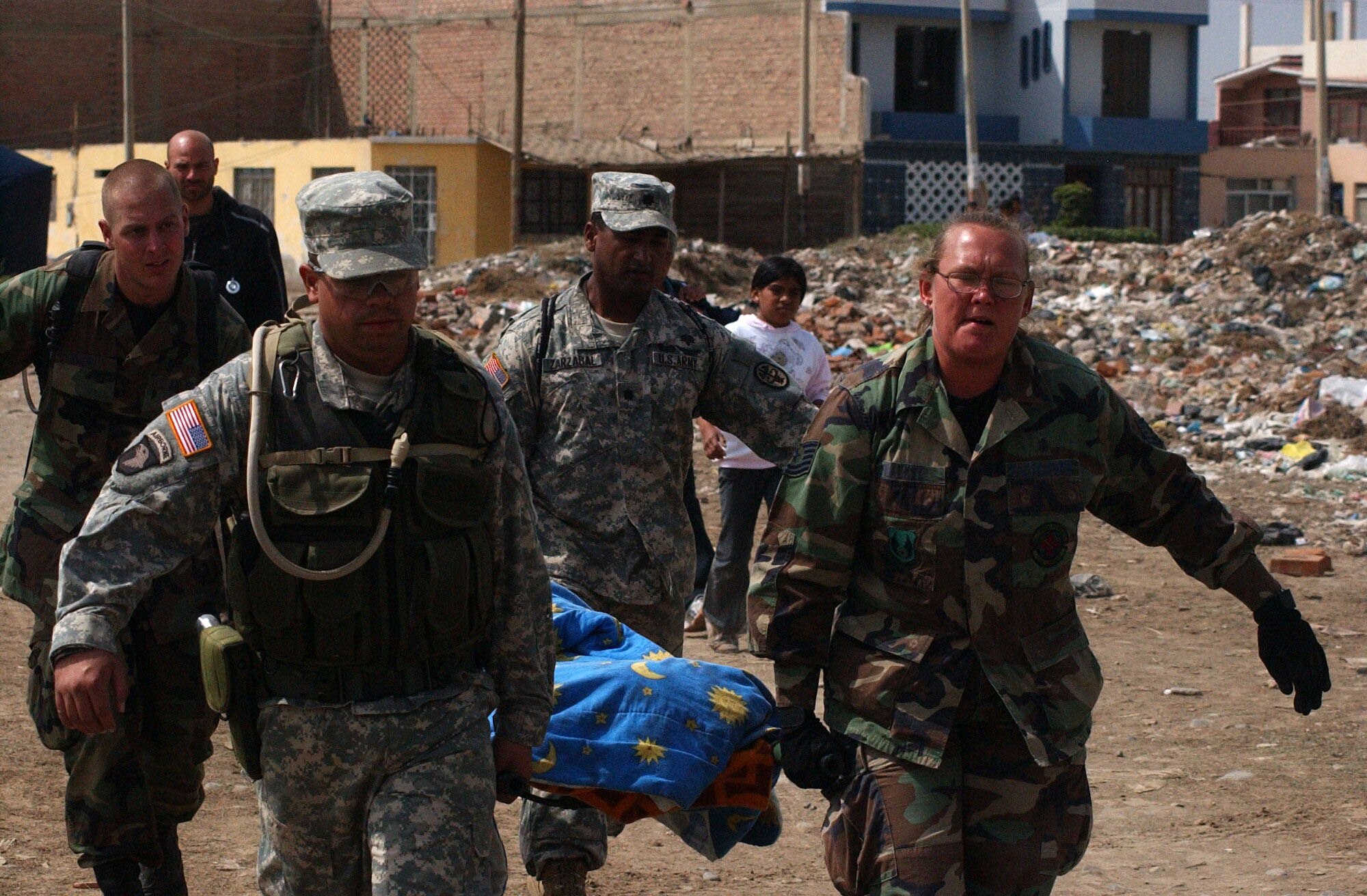 From left, Senior Airman Shaun Emery, Army Specialist Jose Hernandez, Army Lt. Col. Eduardo Zarzabal and Tech. Sgt Mellisa Walker, from the Joint Task Force-Bravo medical humanitarian relief team, carry a woman from her home to the site of the team's medical care site. The task force deployed Aug. 17 to provide medical humanitarian assistance to the citizens of Pisco, Peru following an 8.0 magnitude earthquake Aug. 15. U.S. Army photo by Specialist Grant Vaught.
