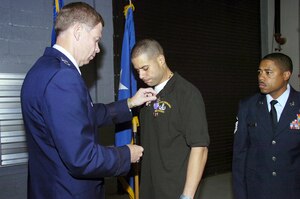 Maj. Gen. Del Eulberg pins a Purple Heart medal on Maj. Jose L. Rivera-Hernandez during ceremonies held in his honor at the 316th Civil Engineer Squadron Explosive Ordinance Disposal Detachment Aug. 16. Maj. Rivera was wounded while on convoy duty in Iraq, after his armored HUMVEE hit by an improvised explosive device July 5.