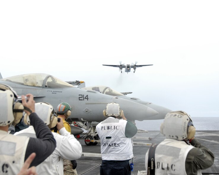 USS NIMITZ, At Sea - International media take pictures as a C-2 approaches the USS Nimitz's flight deck for landing.  Navy personnel refer to the C-2 as carrier on-board delivery, or COD. The Navy uses the COD to deliver passengers and cargo from the carrier to shore and back. The USS Nimitz was one of three aircraft carriers which participated in the exercise. (Photo by Airman 1st Class Daniel Owen/ 36th Wing Public Affairs)