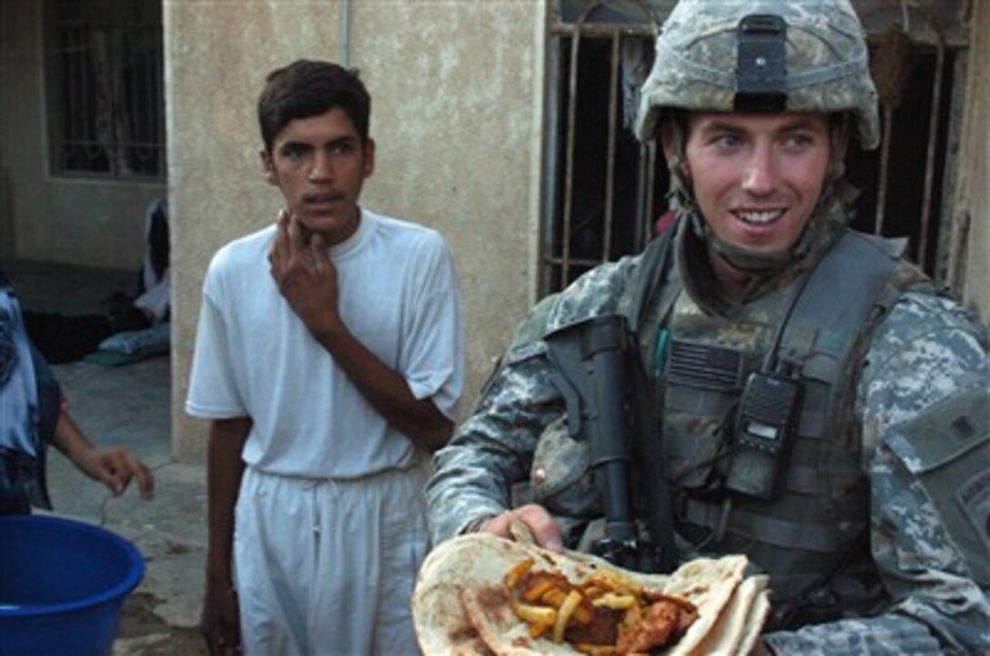 U.S. Army 1st Lt. Brandon Whitis beams with delight after being given a meal on flat bread by an Iraqi man and woman in the Diyala River Valley region of Iraq on Aug. 14, 2007.  Whitis and his fellow soldiers from Bravo Company, 1st Battalion, 505th Parachute Infantry Regiment, 82nd Airborne Division, are patrolling in the region.  