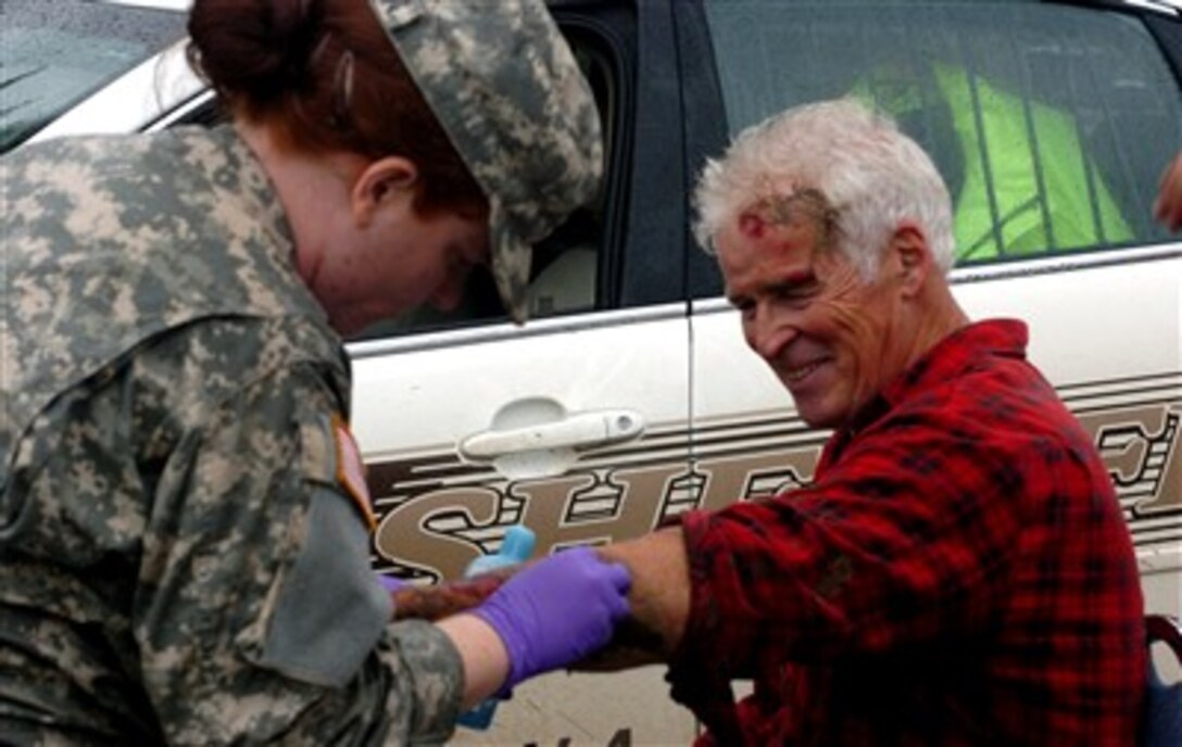 U.S. Army Spc. Pam Anderson, 34th Military Police Company, applies first-aid to an elderly man during flood relief operations just outside Winona, Minn., Aug. 20, 2007. Minnesota National Guard troops responded to the state-of-emergency flooding situation to assist local law enforcement and members of the community. 