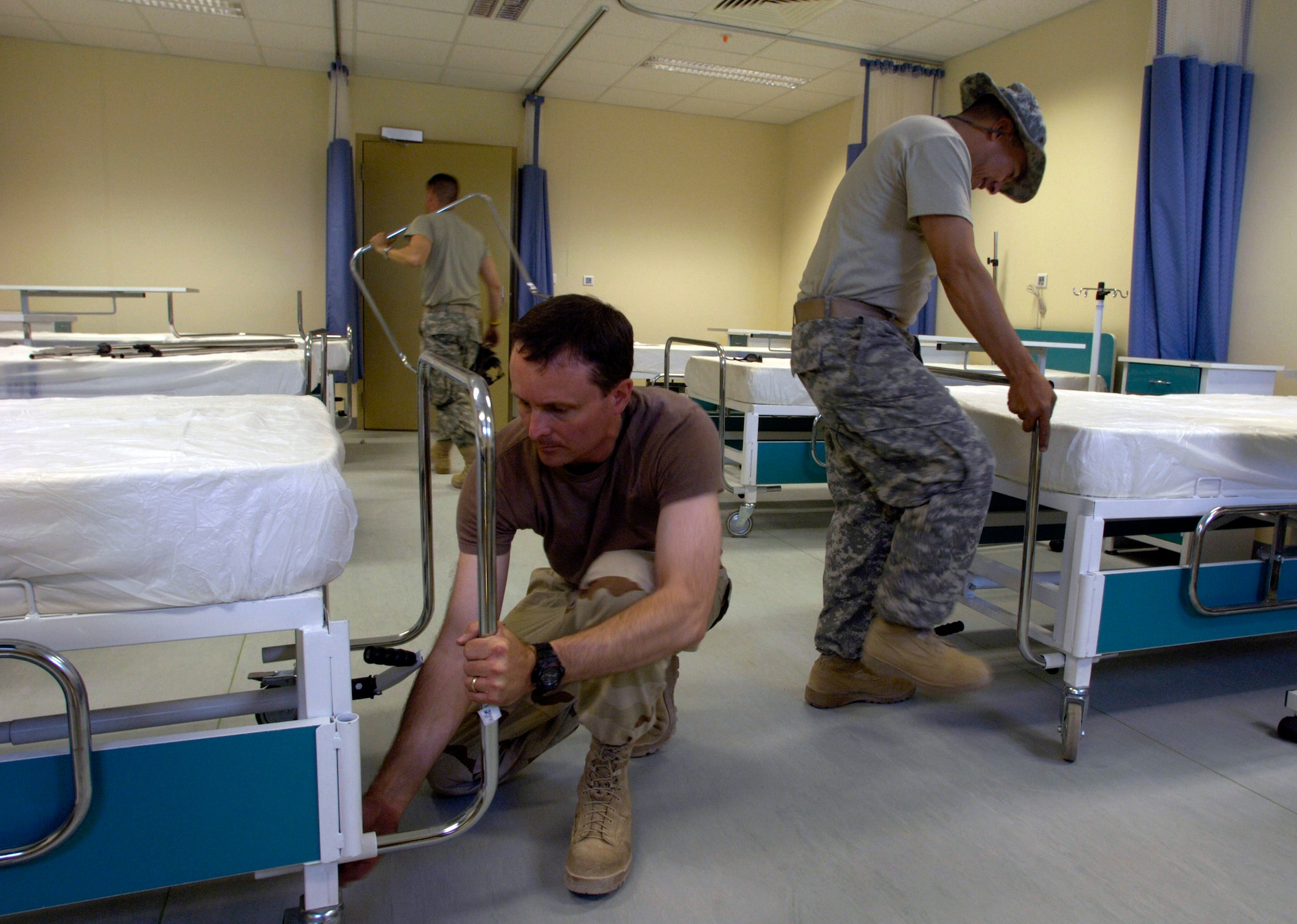 Lt. Col. Gil Weston (foreground), Master Sgt. Doug Suddueth (right background) and Army Sgt. 1st Class Antonio Rivas install hospital beds Aug. 18. The beds were transported from a warehouse across the street to the newly built $6.5 million, 50-bed hospital on the Afghan National Army's Hero Camp, located just outside Kandahar Airfield in southern Afghanistan. Colonel Weston is a medical health facilities planner deployed from Atlanta. Sergeant Suddueth is a medical logistics technician deployed from Maxwell Air Force Base, Ala. Sergeant Rivas is deployed from Ft. Sam Houston, Texas. They are assigned to the Combined Security Transition Command-Afghanistan at Camp Eggers, Kabul, Afghanistan. (U.S. Air Force photo/Master Sgt. Jim Varhegyi)