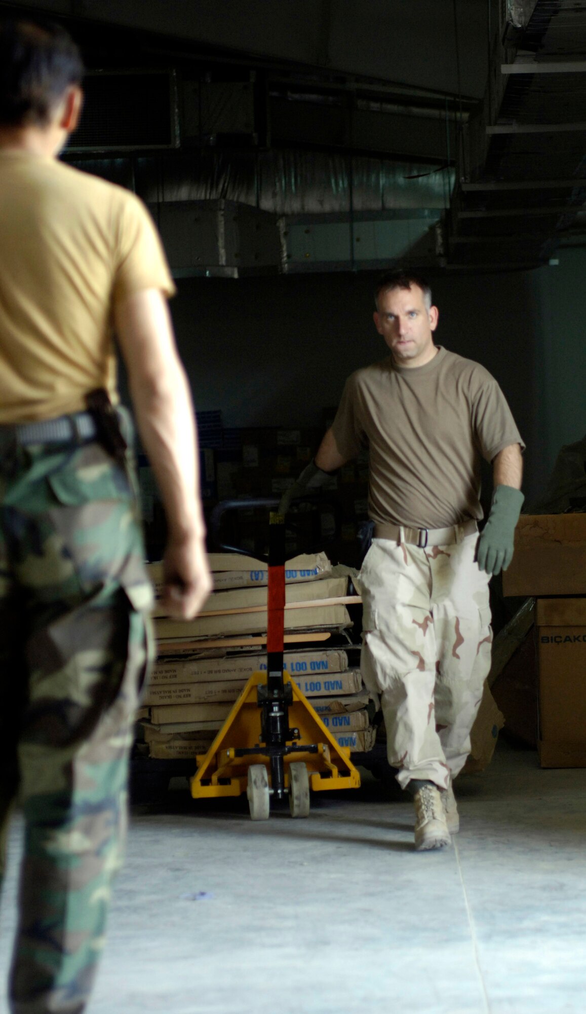 Afghan National Army (ANA) Maj. Abdul Ghafar foreground) waits as his mentor U.S. Air Force medical logistics officer Capt. Jay Snodgrass wheels a pallet of hospital equipment out of their warehouse for installation in a newly built $6.5 million 50 bed ANA hospital on Saturday, August 18, 2007. The state-of-the-art facility is located on the ANA's Hero Camp, just outside of Kandahar Airfield in southern Afghanistan. Major Ghafar is the ANA's 205th Hero Corps warehouse commander. He is also in charge of all logistical support for the 205th. Captain Snodgrass is deployed from Moody Air Force Base, Ga., and is assigned, as an ANA mentor, directly to the 205th Corps. A team of U.S. military medical technicians and logisticians assigned to the Combined Security Transition Command-Afghanistan (CSTC-A) headquartered on Camp Eggers, Kabul, Afghanistan, traveled to Kandahar to assist ANA medical technicians from the 205th in standing up their new hospital. CSTC-A partners with the Government of the Islamic Republic of Afghanistan and the international community, to plan, program, and implement structural, organizational, institutional and management reforms of the Afghanistan National Security Forces. The 500+ military members assigned to CSTC-A provide mentorship and training to the Afghan National Army and to the Afghan National Police in order to develop a stable Afghanistan, strengthen the rule of law, and deter and defeat terrorism within its borders. (U.S. Air Force photo/Master Sgt. Jim Varhegyi)